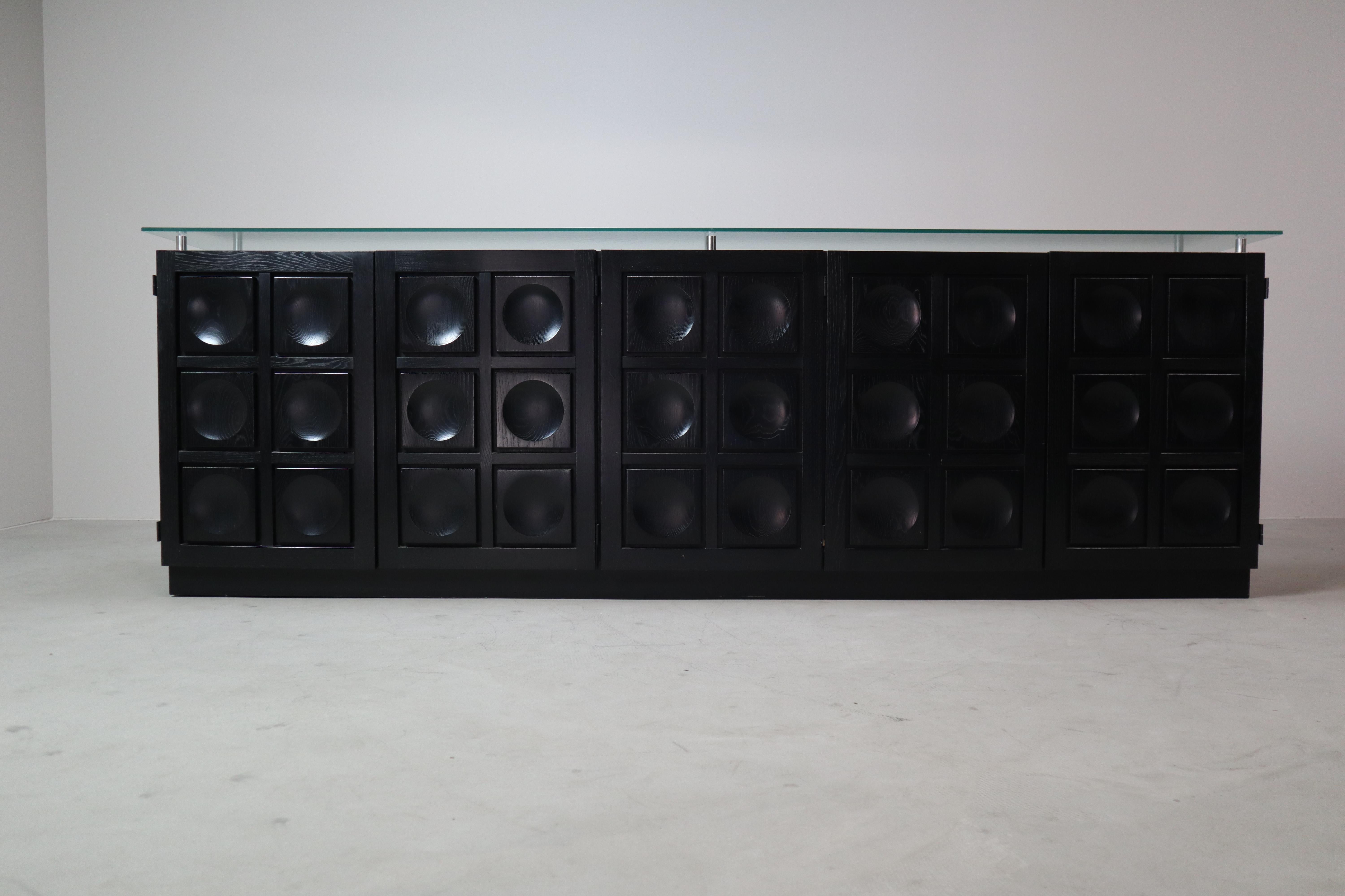 Ce grand et rare buffet de la série Torino du designer belge Frans Defour est un exemple puissant du design brutaliste, réalisé au début des années 1970.
Sa façade présente une grille saisissante de formes circulaires profondément taillées,