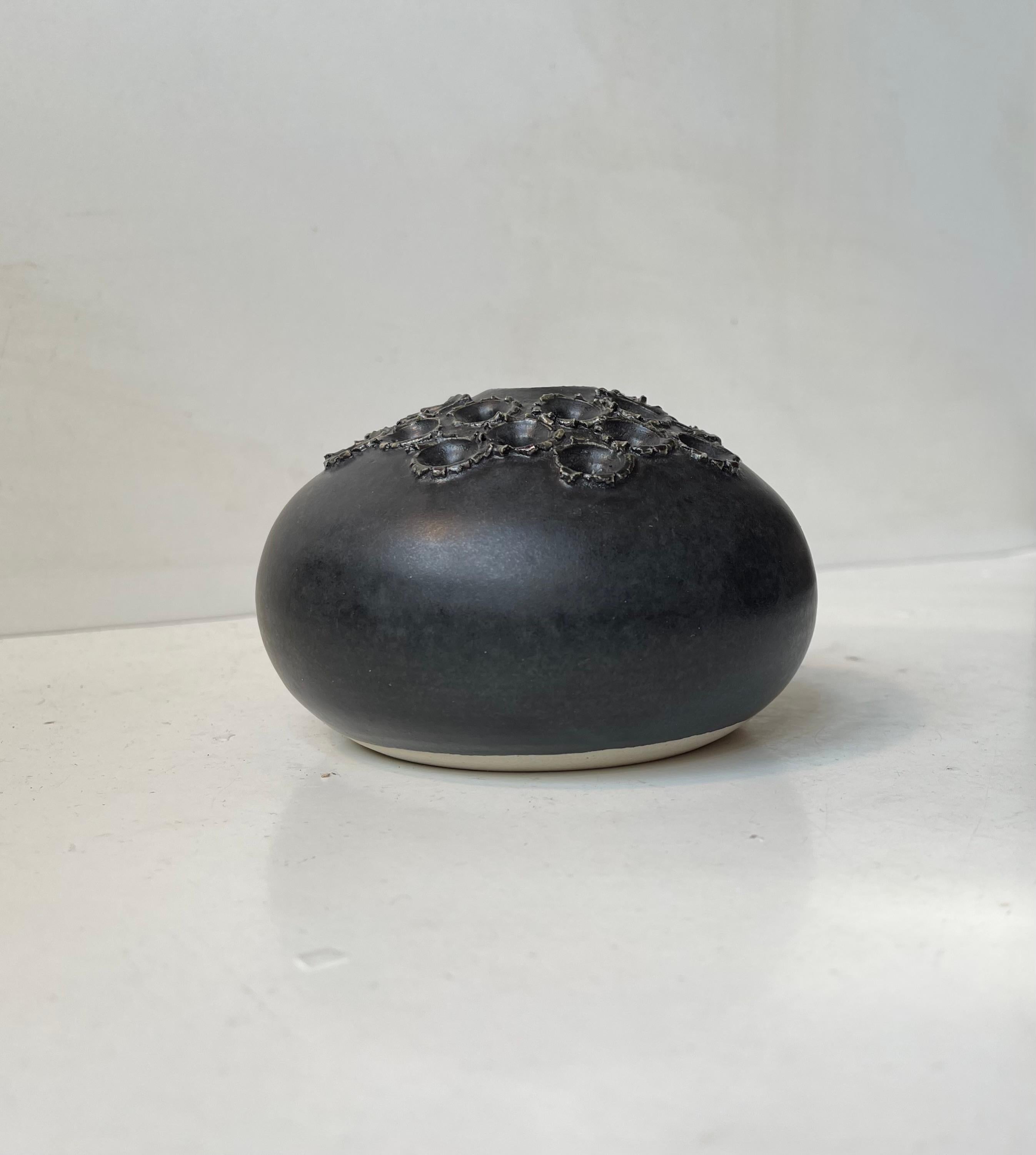 Organically shaped pottery vase with satin black glaze and brutalist decor that doubles as holes for cut flower arrangement. Designed by danish ceramist Aage Würtz in the early 1970s. Its signed to the base. Measurements: D: 12 cm, H: 7 cm.
