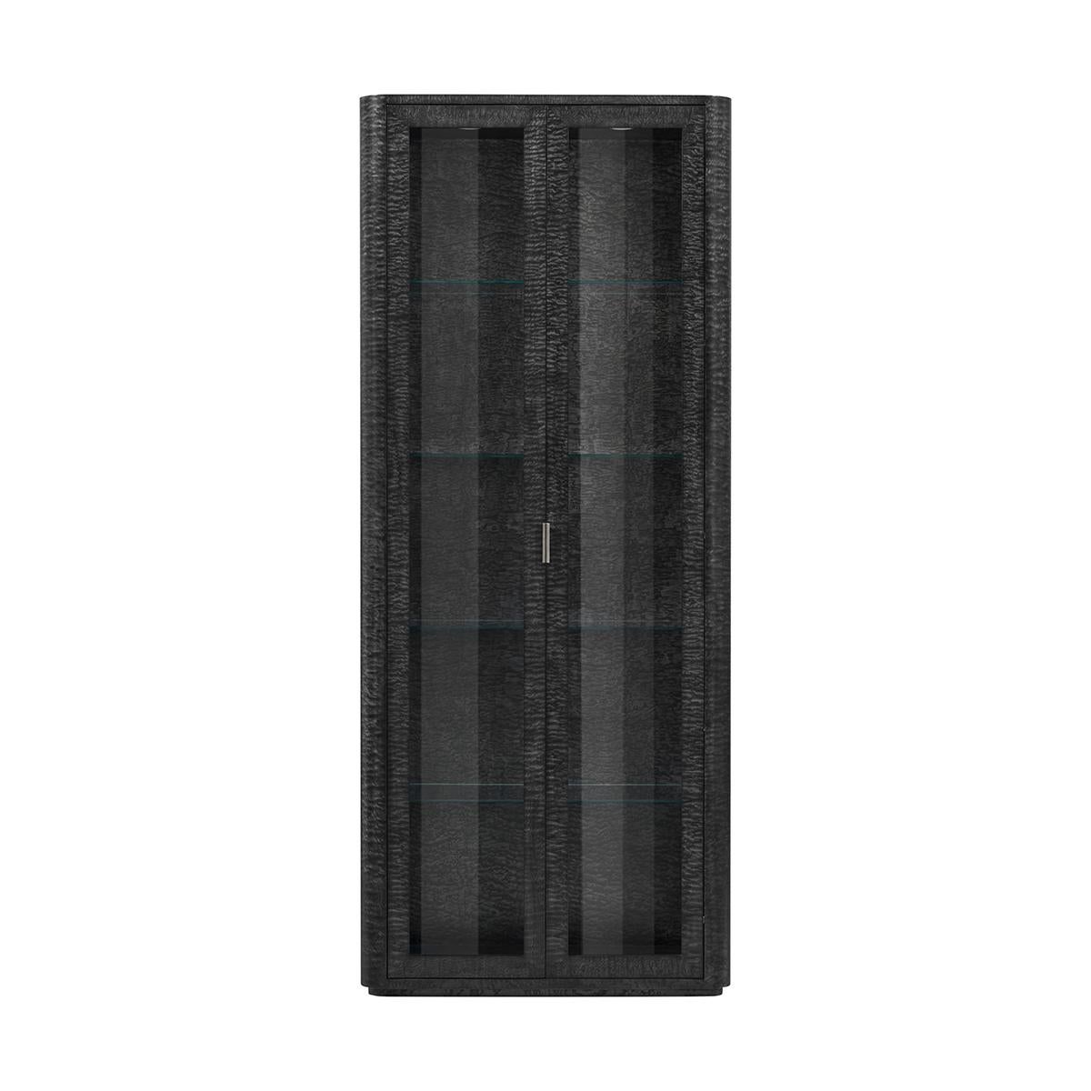 Rifinito in una lussuosa finitura nera silenziosa con accenti in ottone, questo mobile emana un'eleganza e una raffinatezza senza tempo.

L'interno è dotato di ripiani in vetro regolabili, che ti permettono di personalizzare l'esposizione delle tue