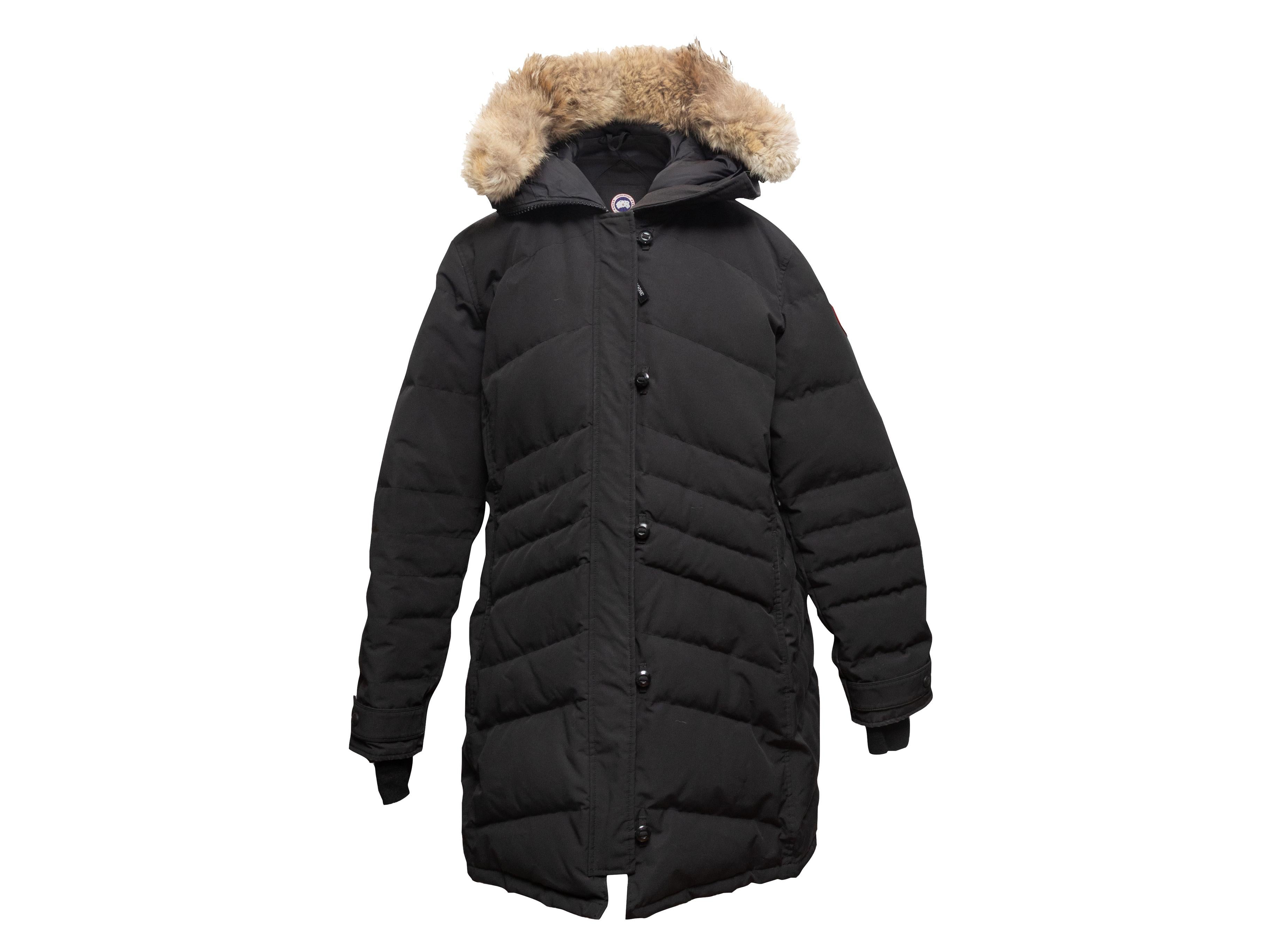 Cappotto con cappuccio nero in piuma d'oca trapuntata di Canada Goose. Doppie tasche sui fianchi. Profili in pelliccia sul cappuccio. Chiusura frontale con zip e bottoni. Busto 45