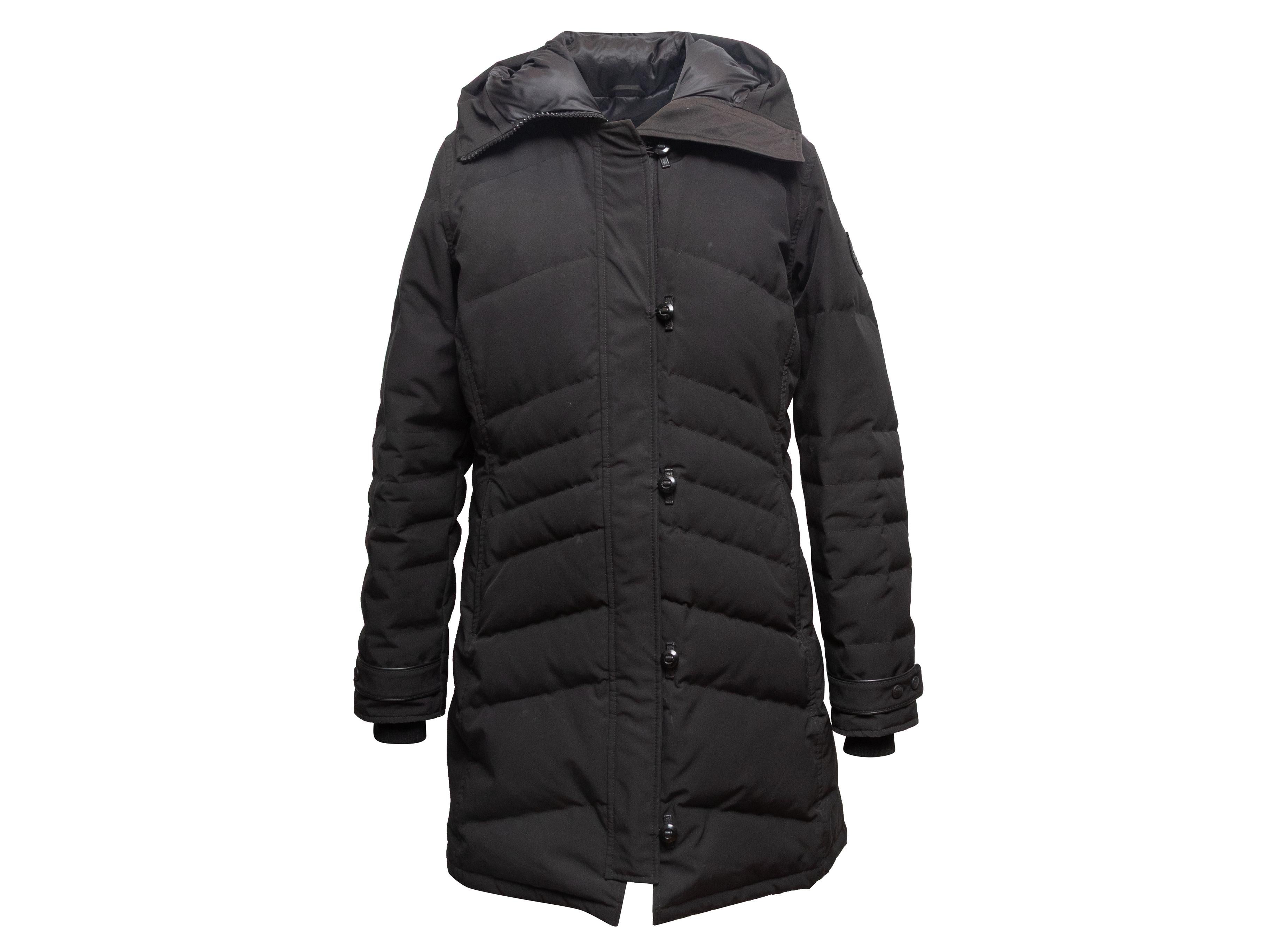 Cappotto con cappuccio nero in piuma d'oca trapuntata di Canada Goose. Doppie tasche sui fianchi. Chiusura frontale con zip nascosta e bottoni. Busto 44