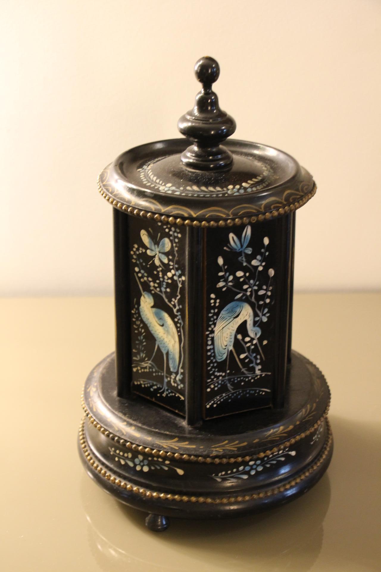 Este antiguo carrusel de puros de principios del siglo XX con caja de música es absolutamente asombroso. Presenta un exterior lacado en negro y detalles metálicos de latón. El humidor dispone de 6 paneles laterales giratorios . Cada panel está