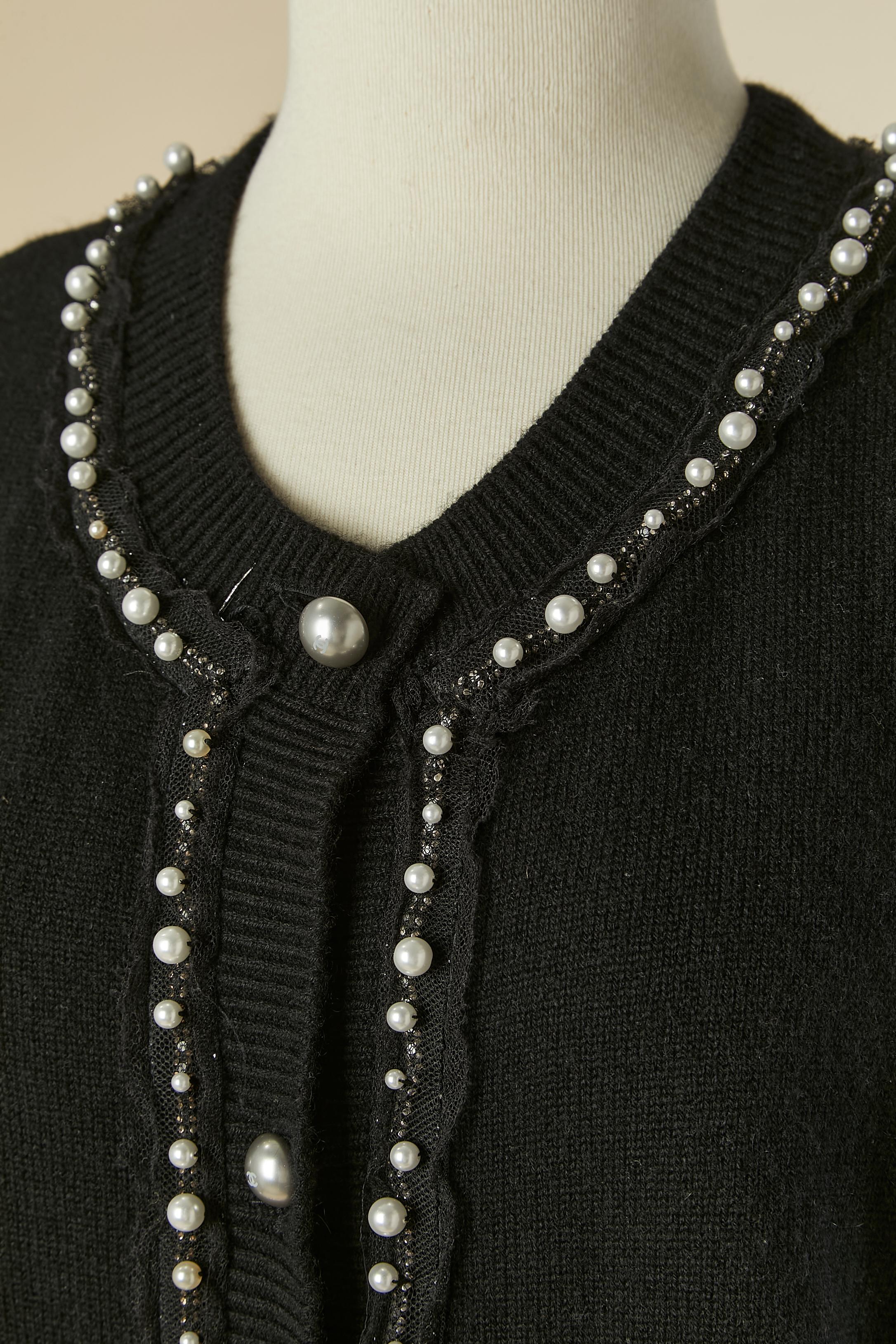 Cardigan en cachemire noir orné de perles et de strass.
Bouton et boutonnière marqués sur le milieu du devant. Tulle, bordé de strass et de perles. taille 42 (FR) L