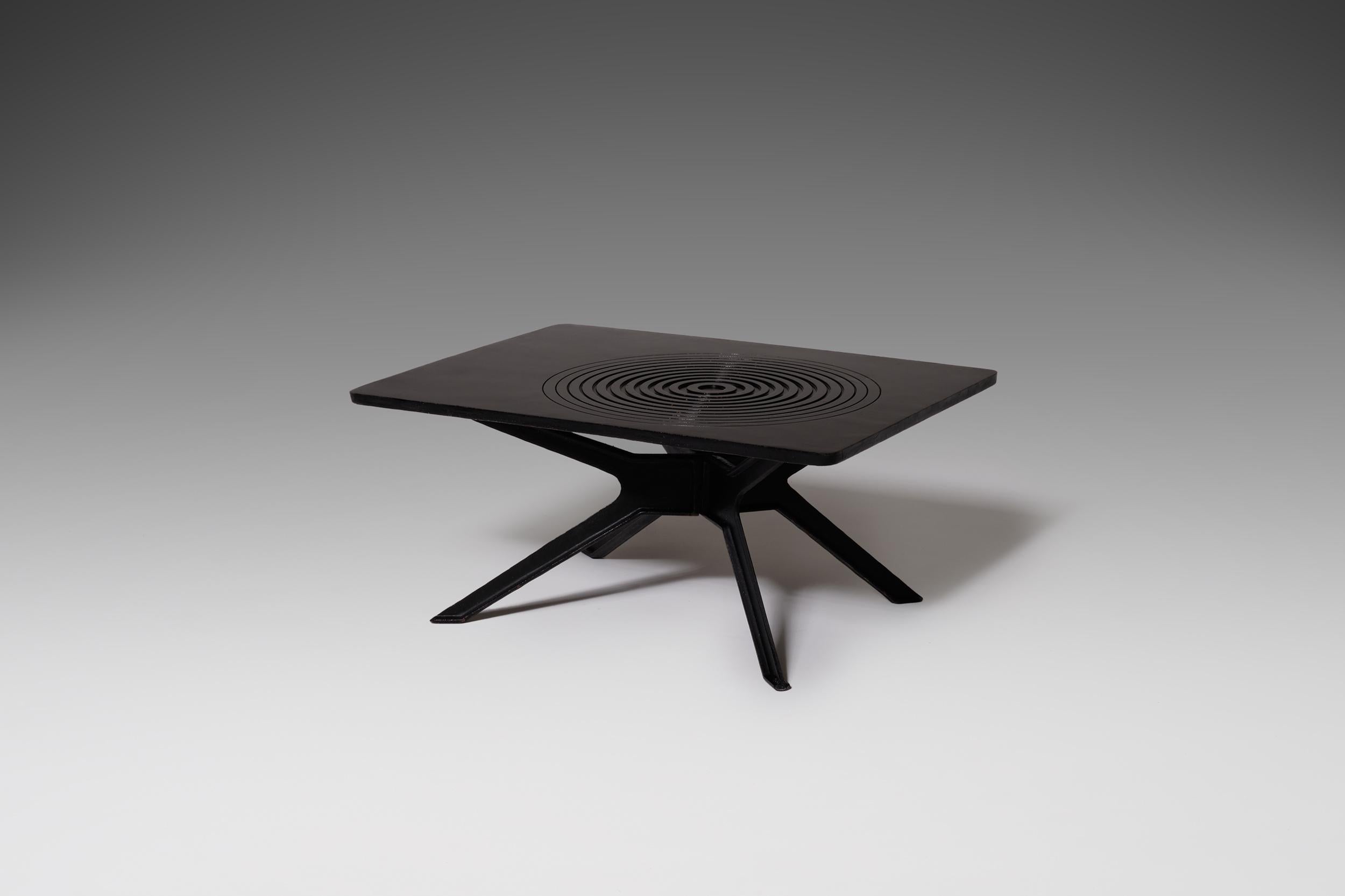 Unusual Brutalist coffee table in cast iron, France, 1960s The heavy black lacquered table top has circular graphic pattern with relief which rests on an asymmetrical shaped base. Unique and artistic appearance.