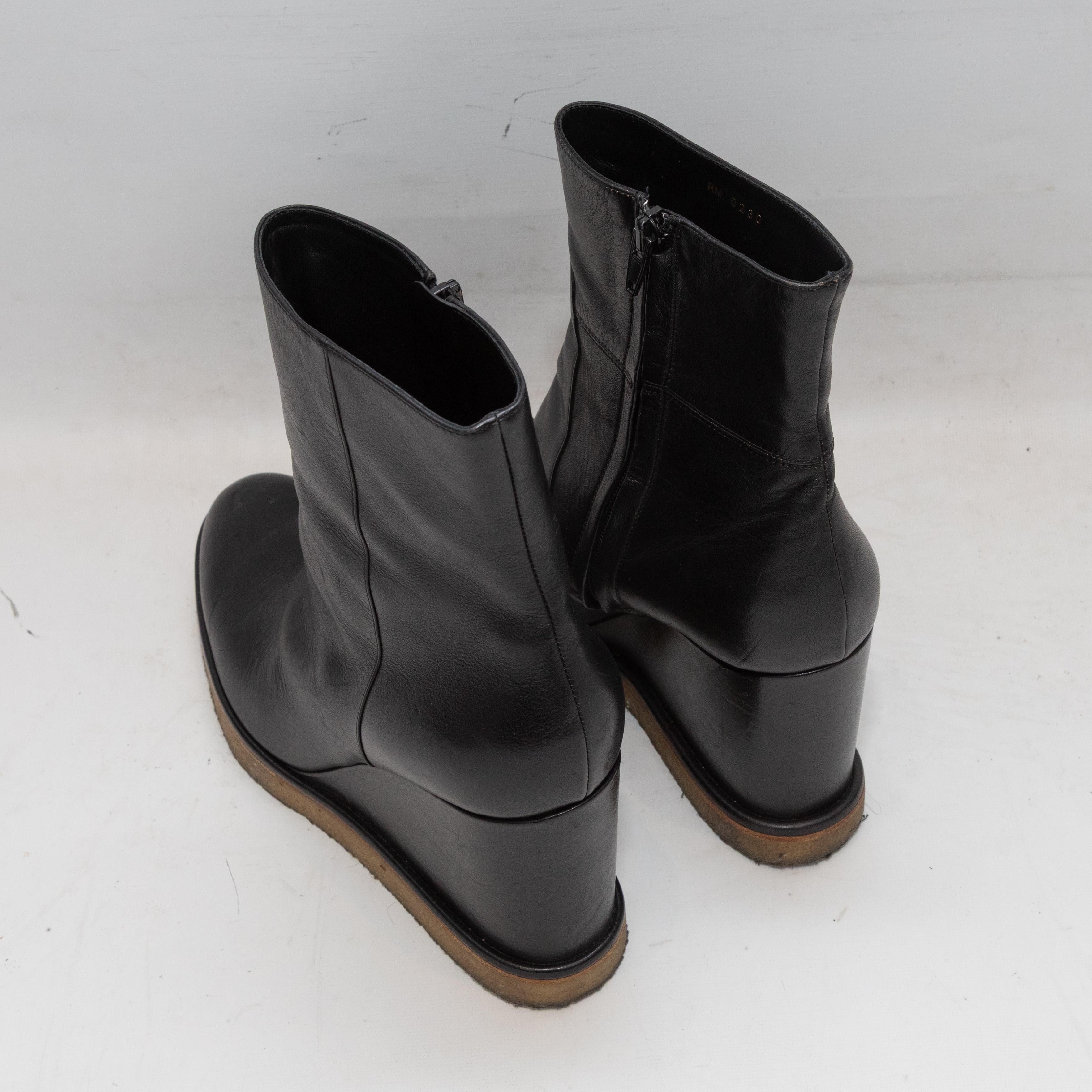  Black leather wedge ankle boots by Celine. Gold-tone hardware accents at outer sides. Zip closures at inner sides. 6