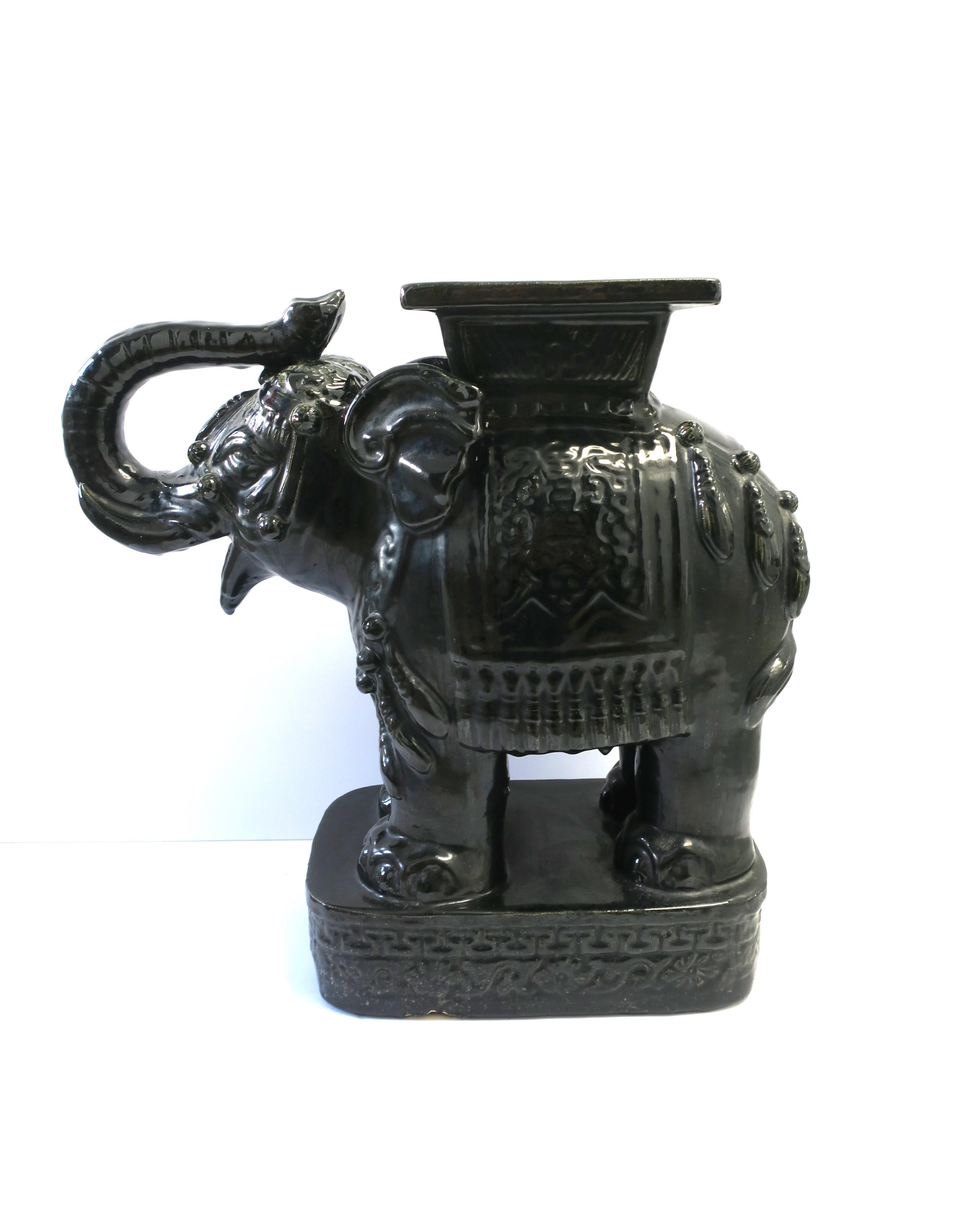 An Italian black glazed ceramic elephant in the Hollywood Regency style, circa mid-20th century, Italy. This all-black ceramic Elephant (with trunk up for good luck) could make a great end table/stand-alone-piece, side/drink table, plant or