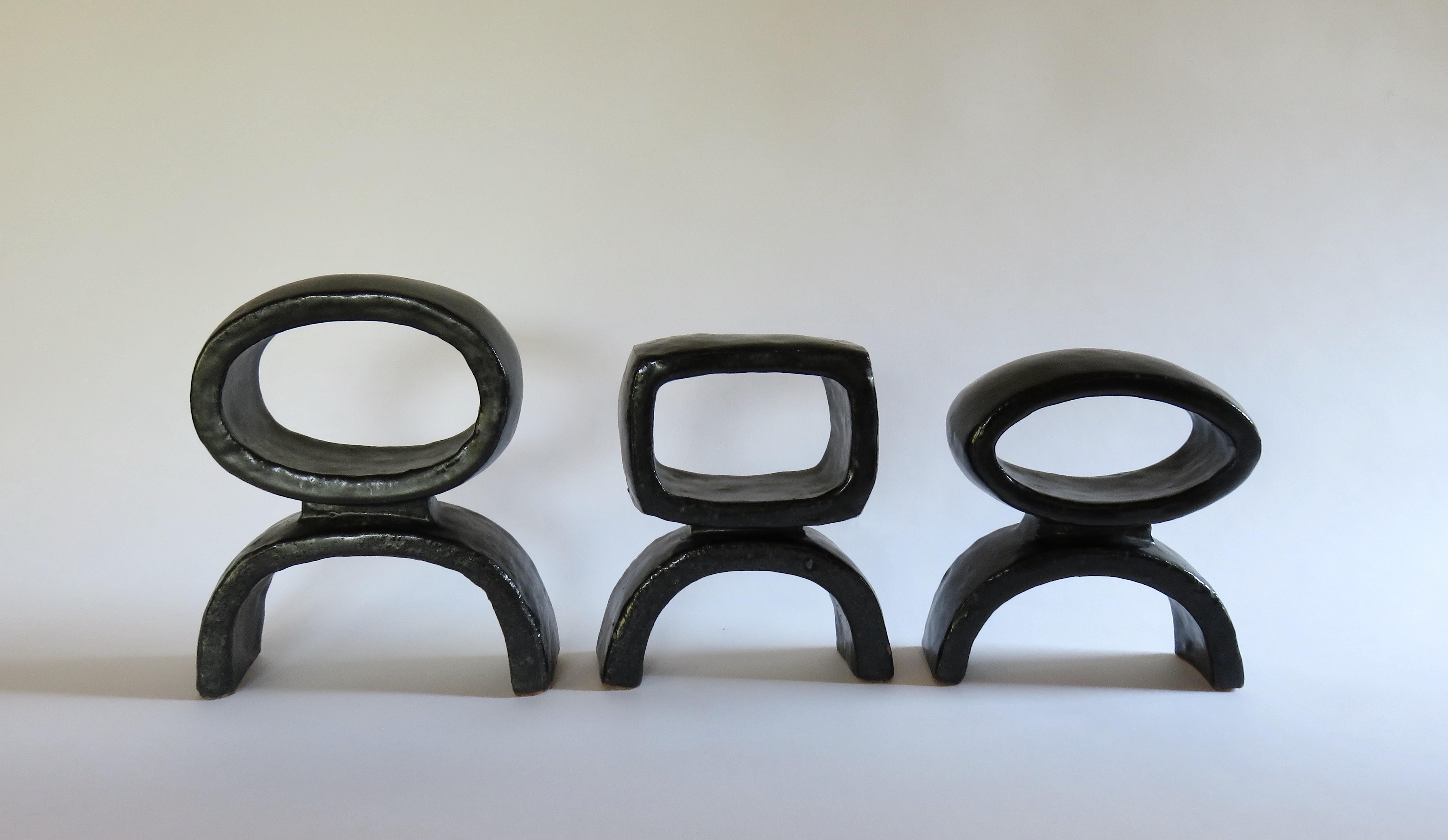 Un trio de 3 céramiques construites à la main  TOTEMs modernes issus d'une série de recherches sur la forme totémique. Chacun est différent, un rectangle souple, un ovale et un anneau circulaire sur des pieds arqués. La glaçure noire satinée du grès