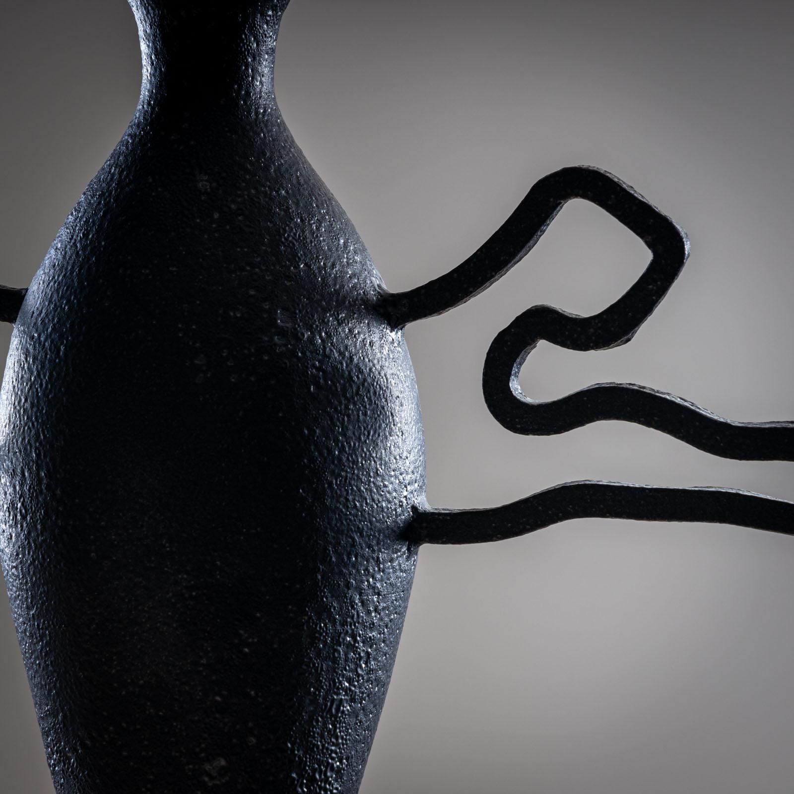 Vaso in ceramica smaltata nera con corpo conico liscio e lunghi manici a forma libera. Firmato POEMU / de Mons / Aix in basso.

Poemu è un artista francese versatile il cui lavoro spazia dalla lirica al canto, dall'illustrazione alle arti visive e
