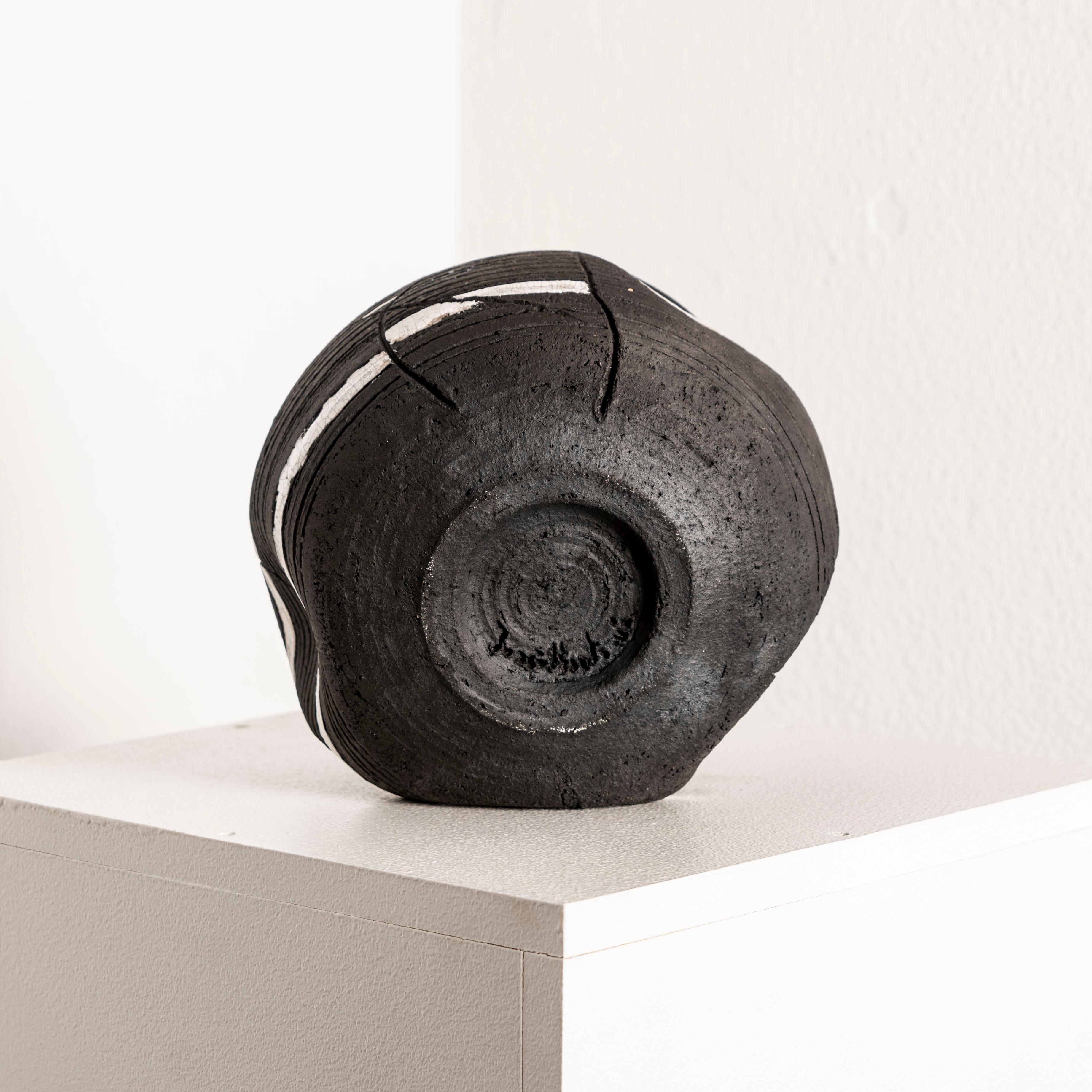 Die Investition in dieses schwarze Keramikgefäß mit weißer Glasur, das vom Künstler signiert ist, bietet eine einzigartige Gelegenheit, ein Stück zeitgenössischer Keramikkunst zu besitzen, das Eleganz und Schlichtheit nahtlos miteinander verbindet.