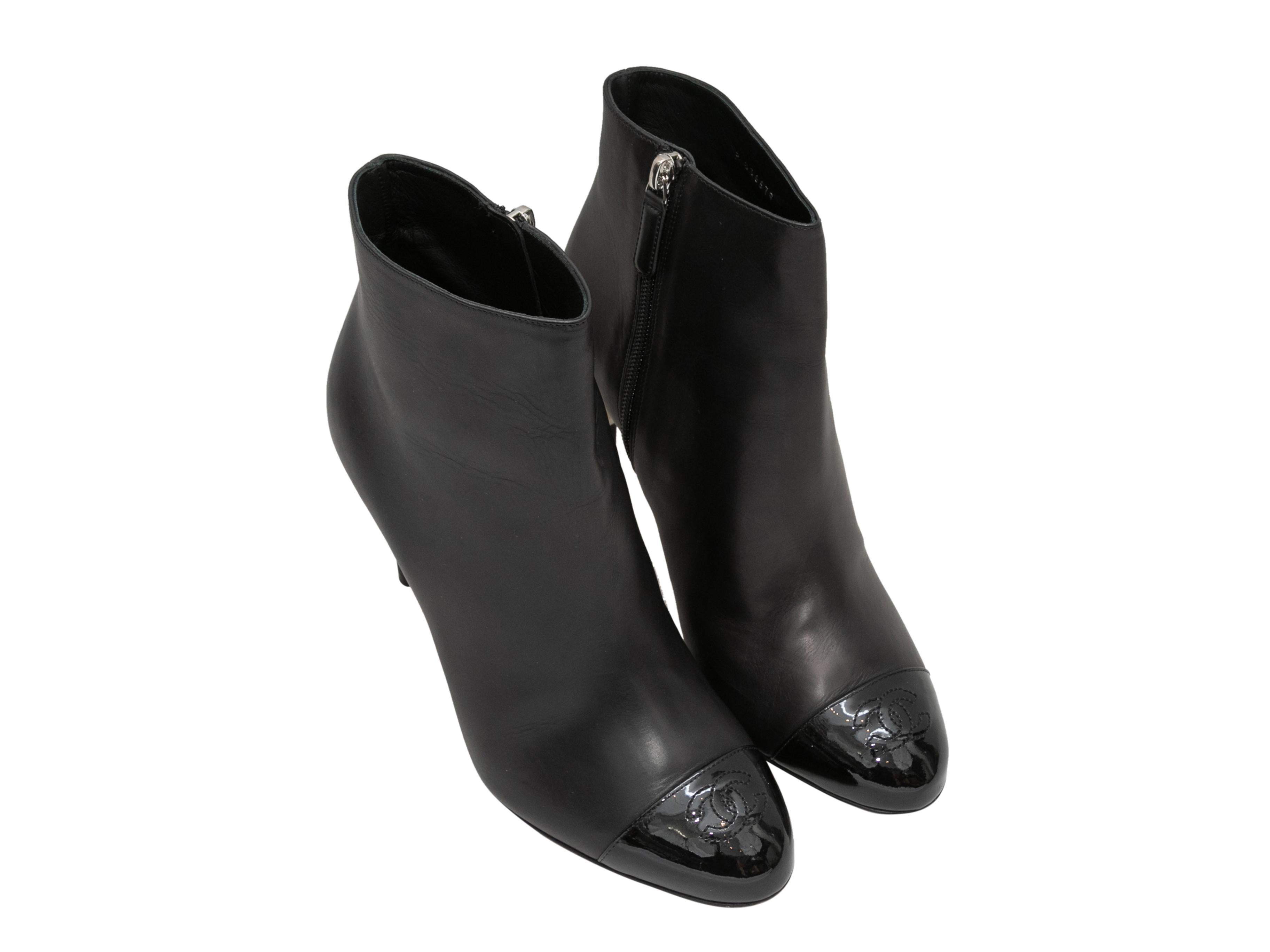 Black leather cap-toe CC ankle boots by Chanel. Faux pearl accents at heels. Zip closures at inner sides. 4.25