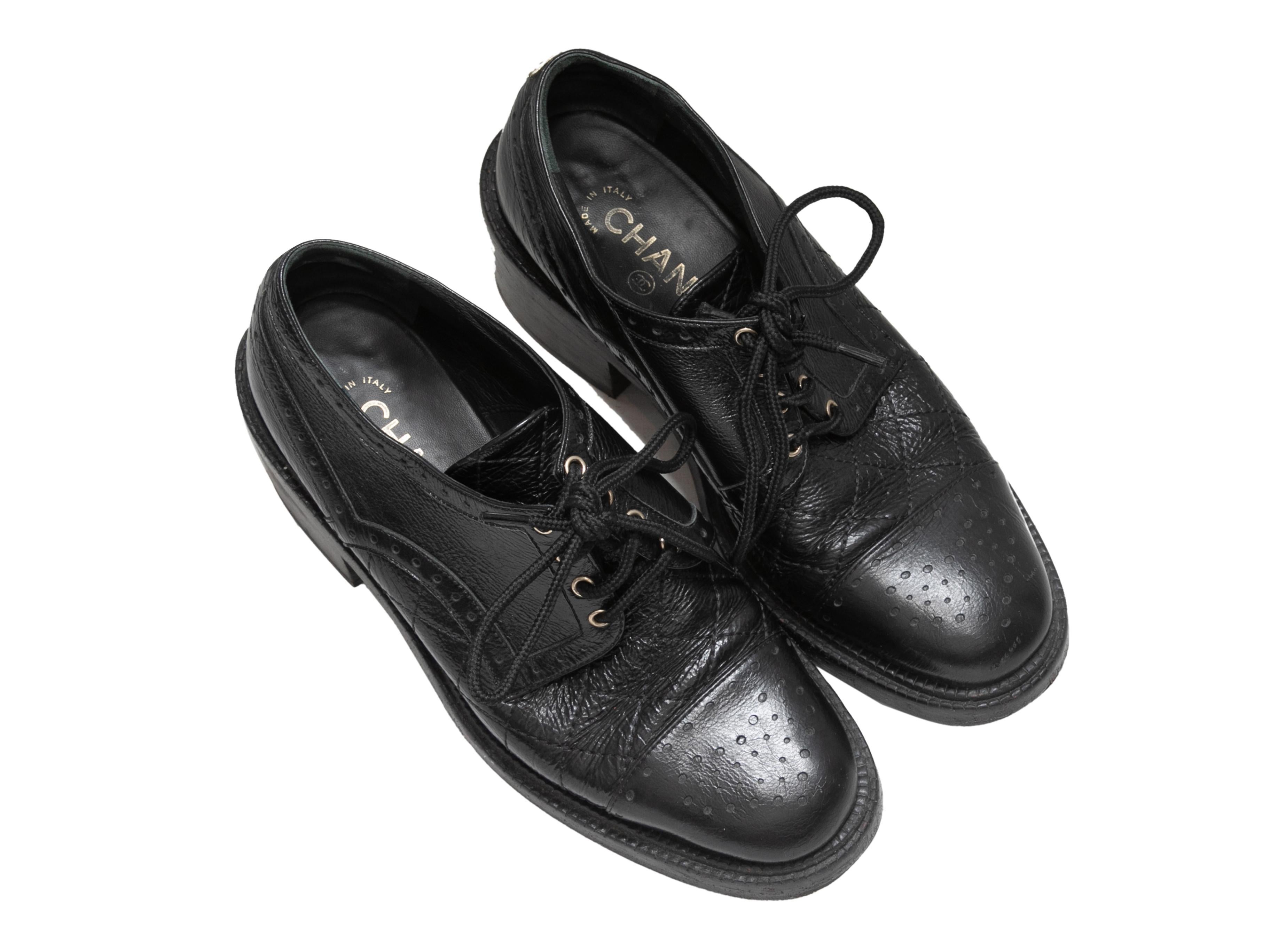  Black patent leather brogue oxfords by Chanel. Stacked heels. Lace-up tie closures at tops. 1