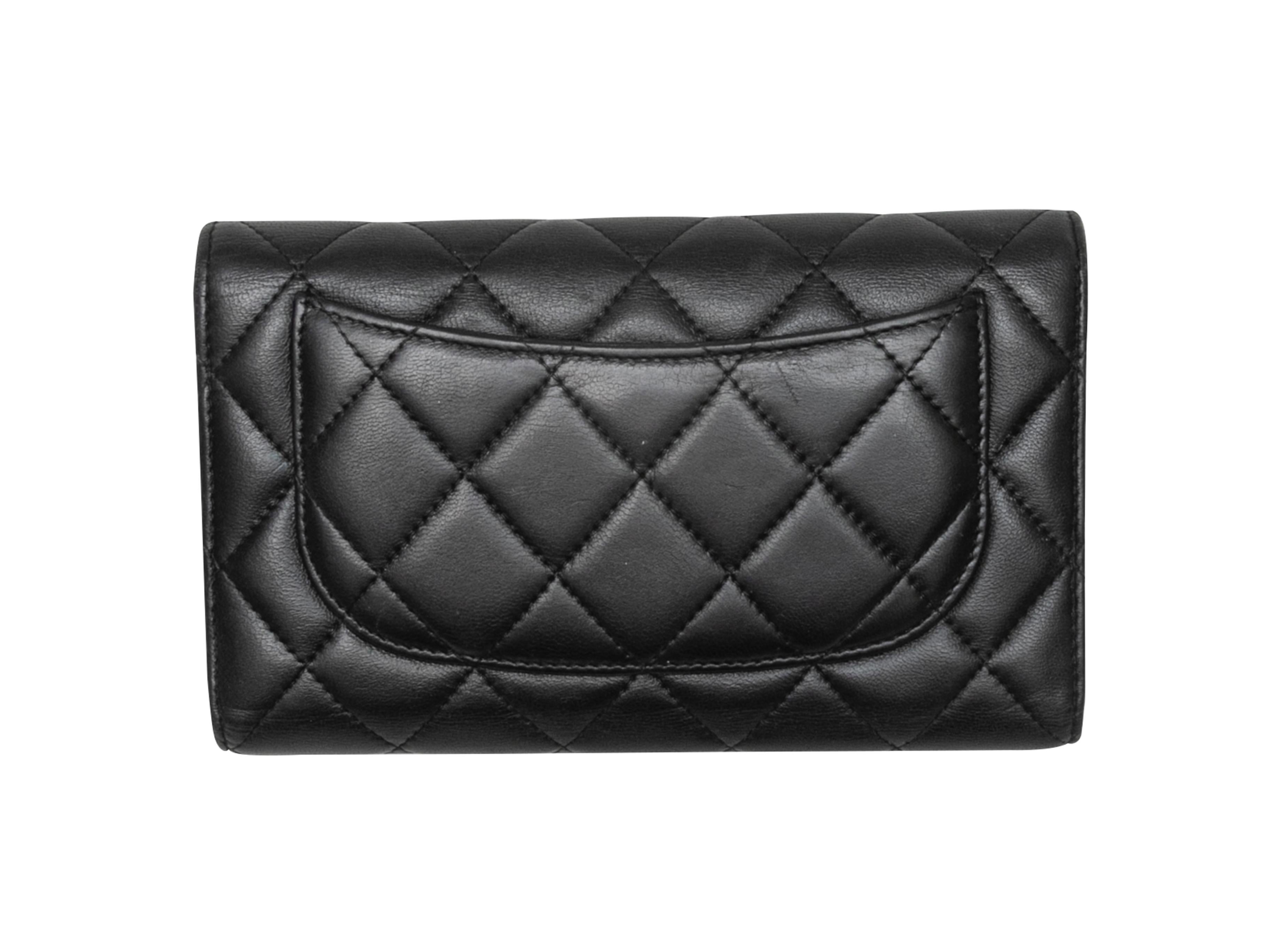 Product Details: Black quilted lambskin leather continental flap wallet by Chanel. Exterior back pocket. Interior card and cash slots. Front CC flap snap closure. 4.5