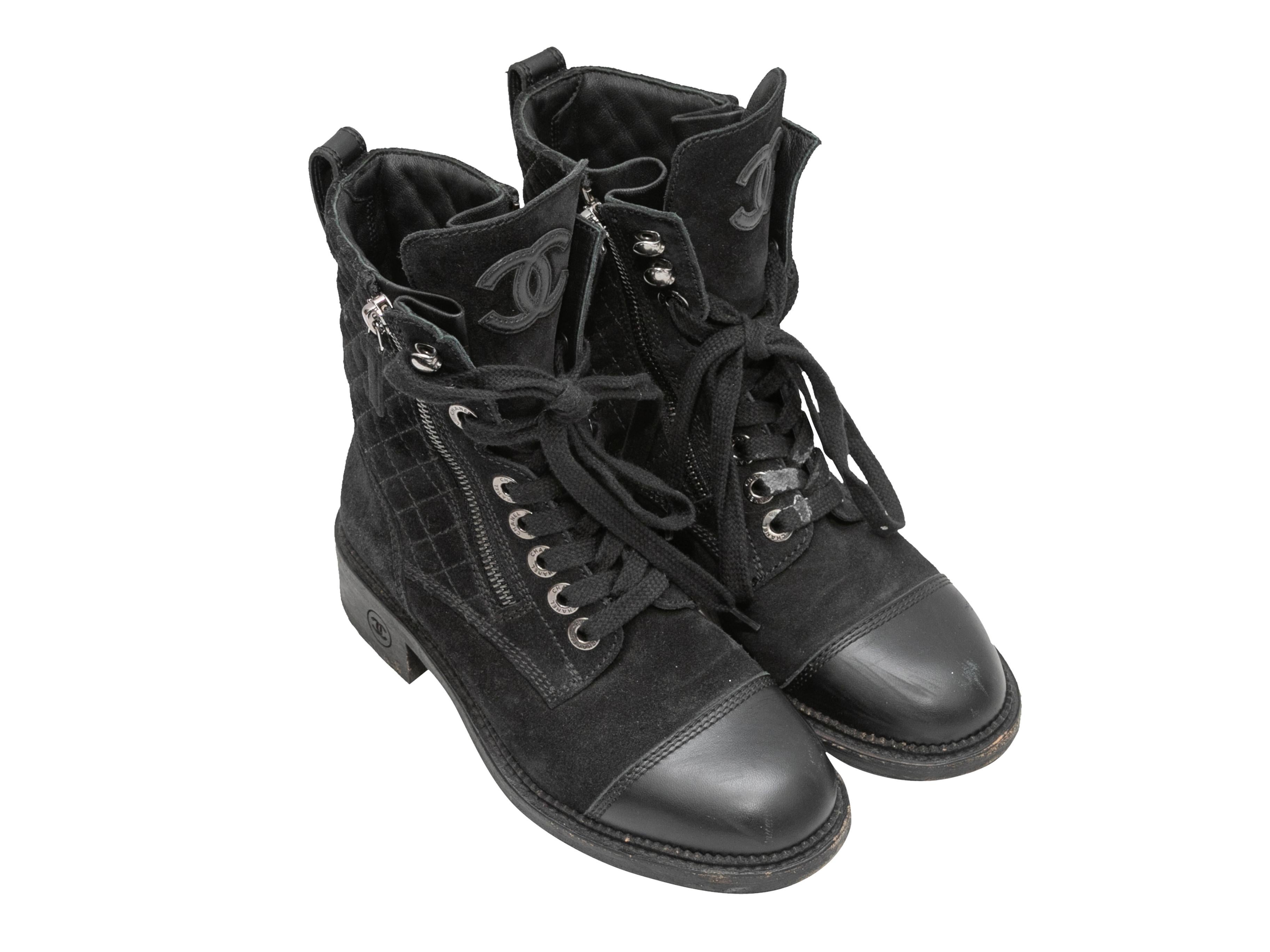 Black quilted suede and leather cap-toe combat boots by Chanel. Lug soles. Stacked heels. Lace-up detailing at tops. Zip closures at sides. 6