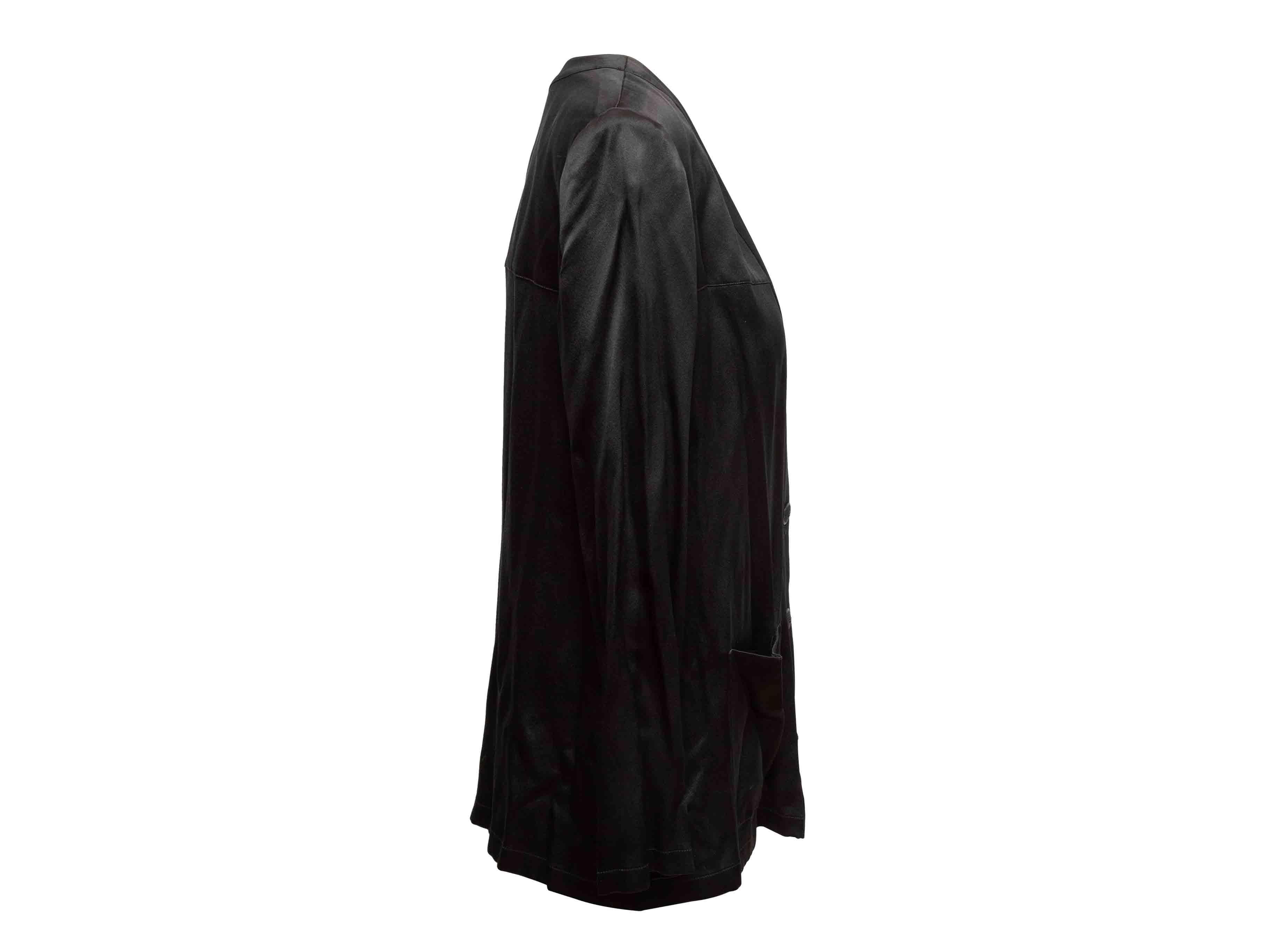 Top a maniche lunghe in seta nera di Chanel. Scollo a V. Doppia tasca frontale. Chiusura con bottoni al centro davanti. Seno 38
