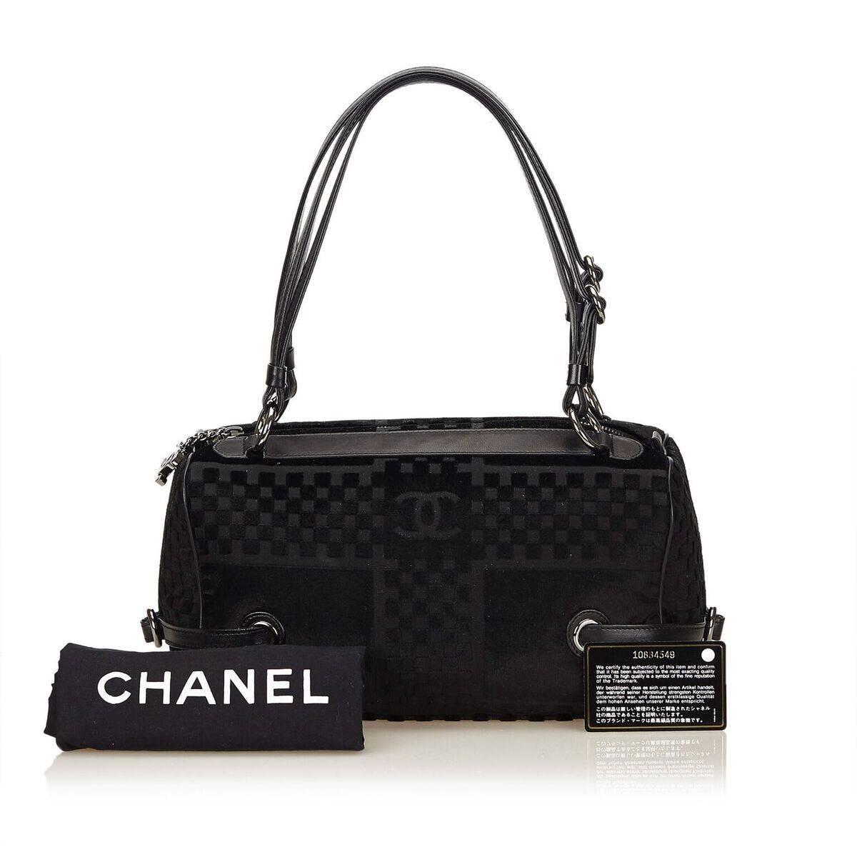 Product details:  Black velour shoulder bag by Chanel.  Trimmed with leather.  Dual shoulder straps.  Top zip closure.  Lined interior with inner zip pocket.  Silvertone hardware.  Authenticity card and dust bag included.  12