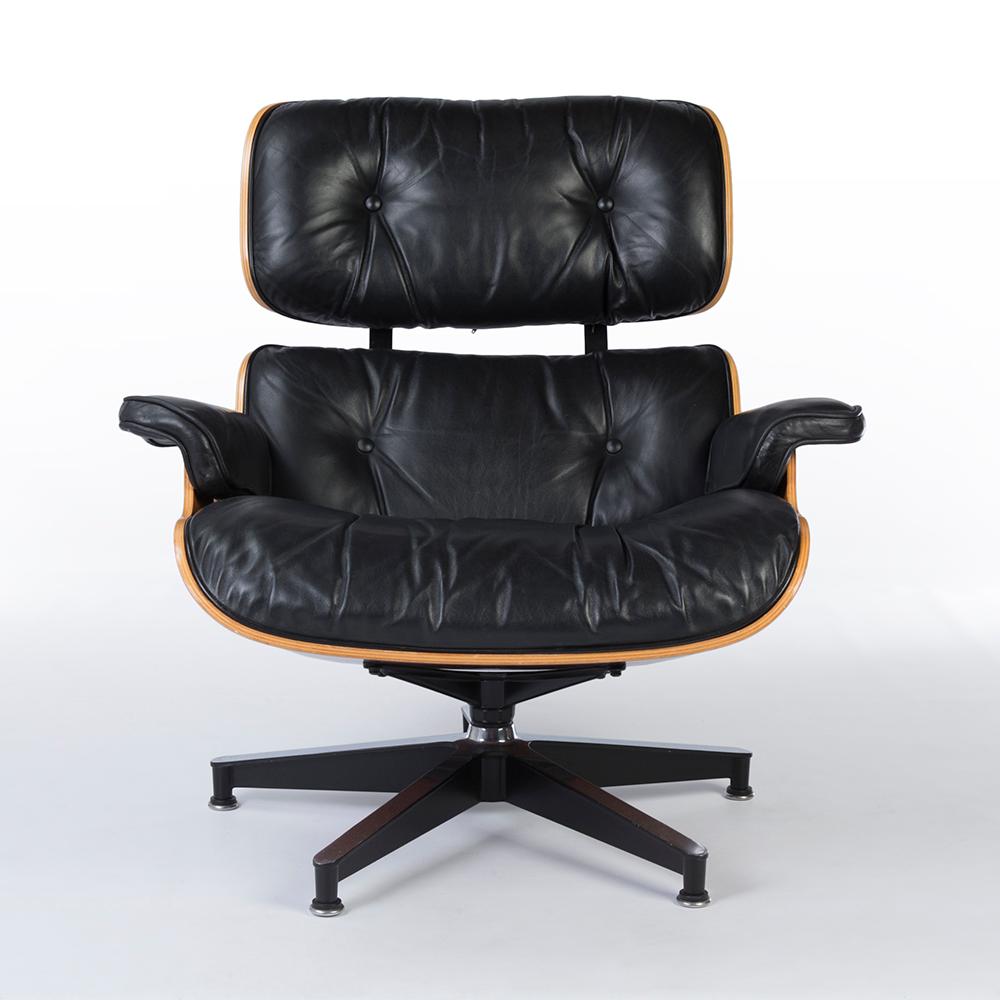 Premium black and cherry Herman Miller lounge chair and ottoman set, completed with a rich cherrywood veneer, enclosed by a gorgeous black leather. As with age, there are some minor scratches, particularly on the rounded wood panels. The color of