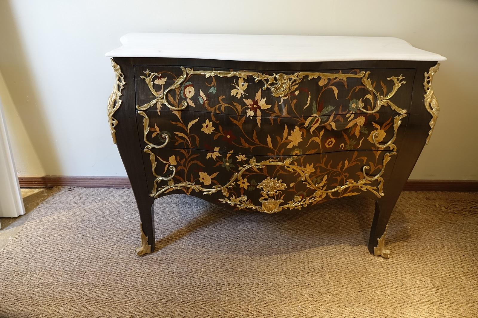Beautifully made chest of drawers, inlaid with hand cut marquetry covering the front and sides. The style is traditional Louie XV with an oriental influence (chinoiserie) in the marquetry details. The effect is finished with bronze detailing acting