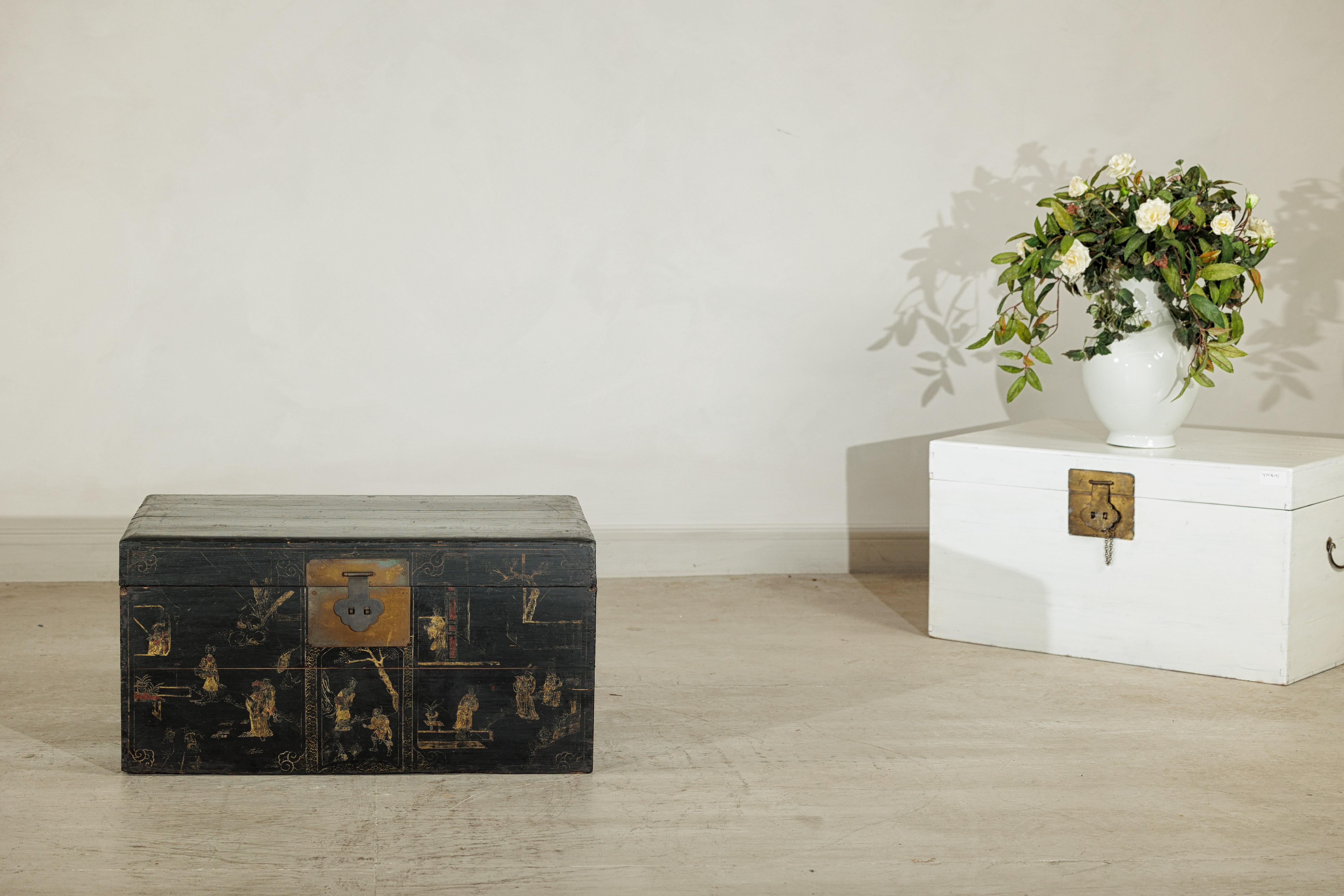 Ce coffre à couvertures chinois laqué noir allie rangement fonctionnel et élégance artistique. La forme rectangulaire est richement décorée sur le devant de scènes dorées peintes à la main représentant des personnages de cour et des décors de