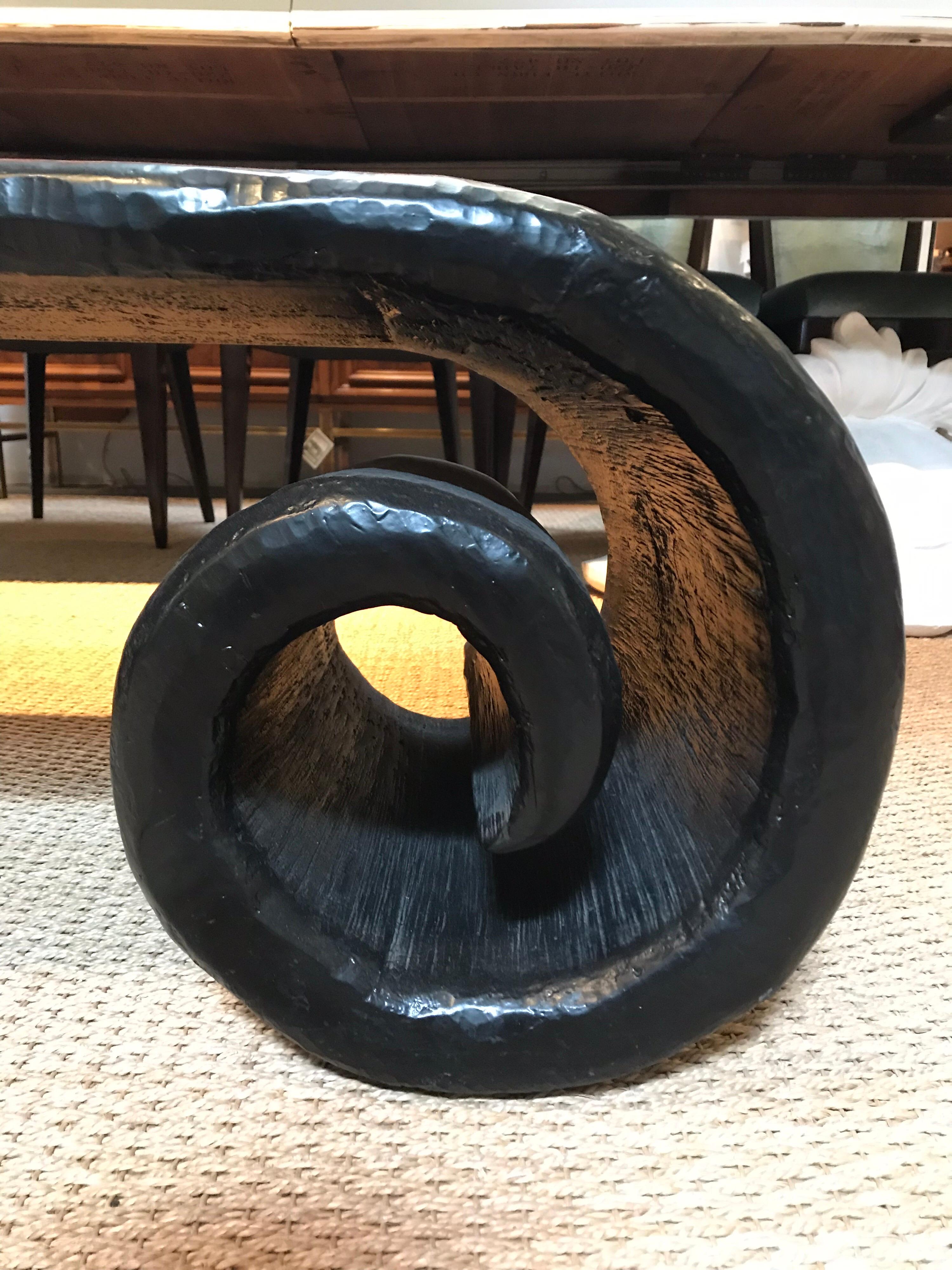 This black, low cocktail table is of Chinese origination and has a handmade element to it. The ends are loosely rolled and curl under the table surface as supports for the 'table-top'.