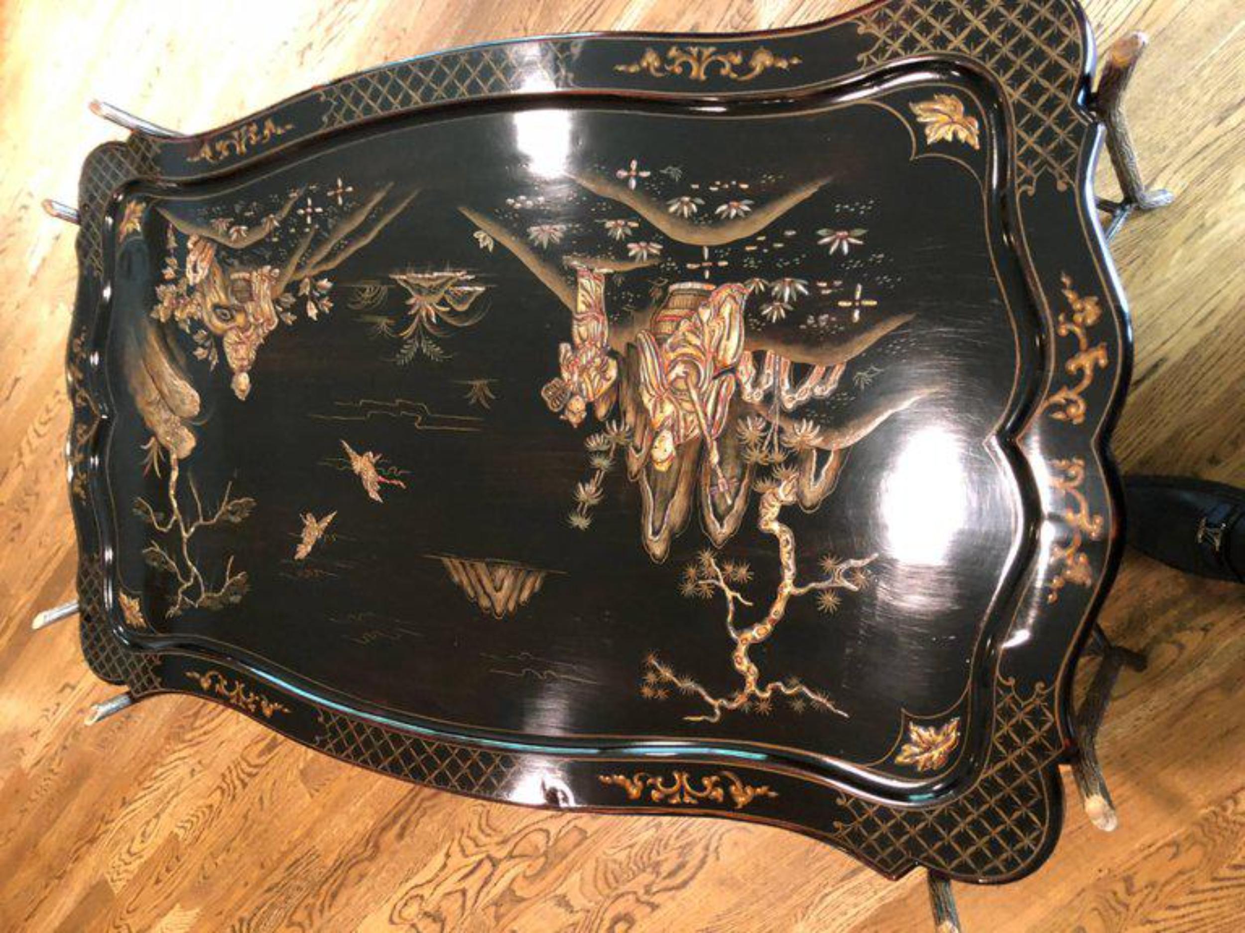 An elegant black chinoiserie coffee or cocktail table. The table features hand-painted gilt decoration of Chinese landscape.
