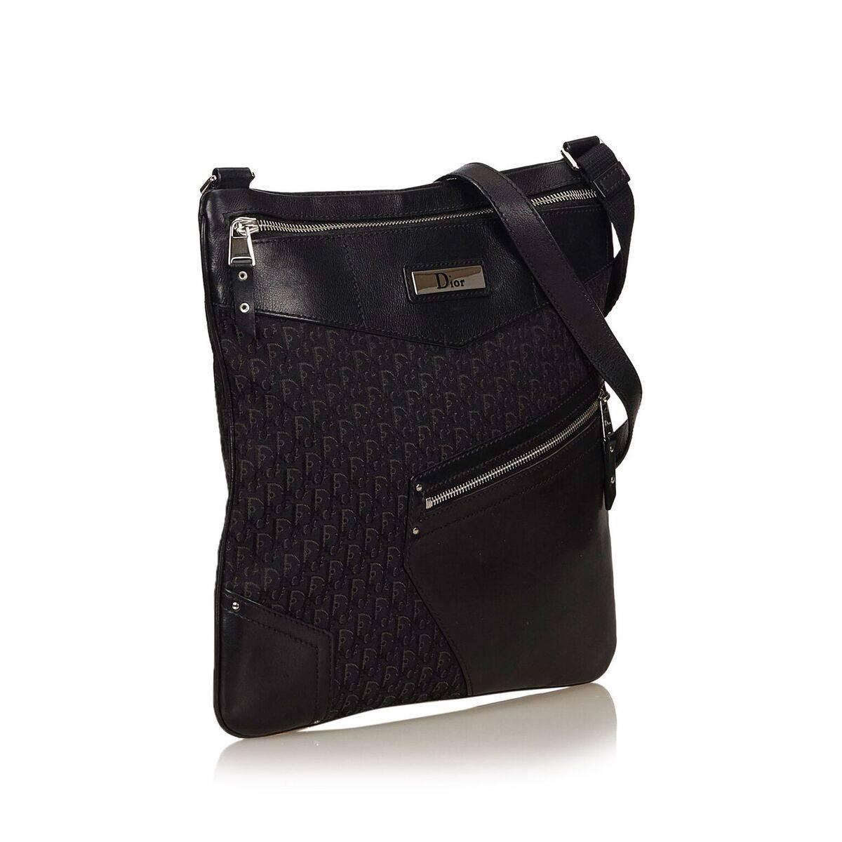 Product details:  Black oblique jacquard crossbody bag by Christian Dior.  Trimmed with leather.  Top zip closure.  Lined interior with inner zip pocket.  Exterior zip pocket.  Silvertone hardware.  11