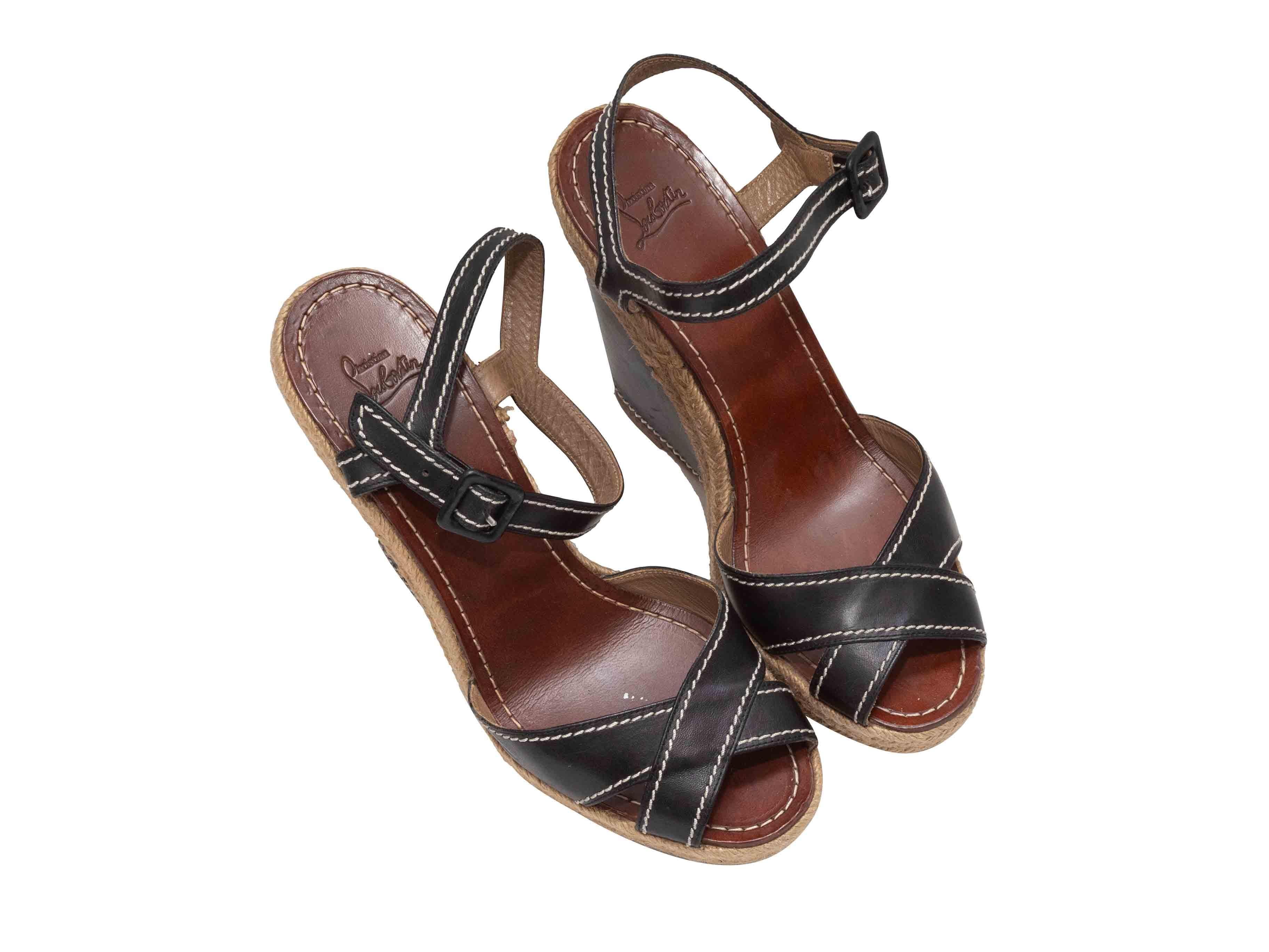 Sandali con zeppa espadrillas in pelle nera e iuta di Christian Louboutin. Cuciture a contrasto su tutta la superficie. Chiusura con fibbie alla caviglia. Altezza plateau 1,5