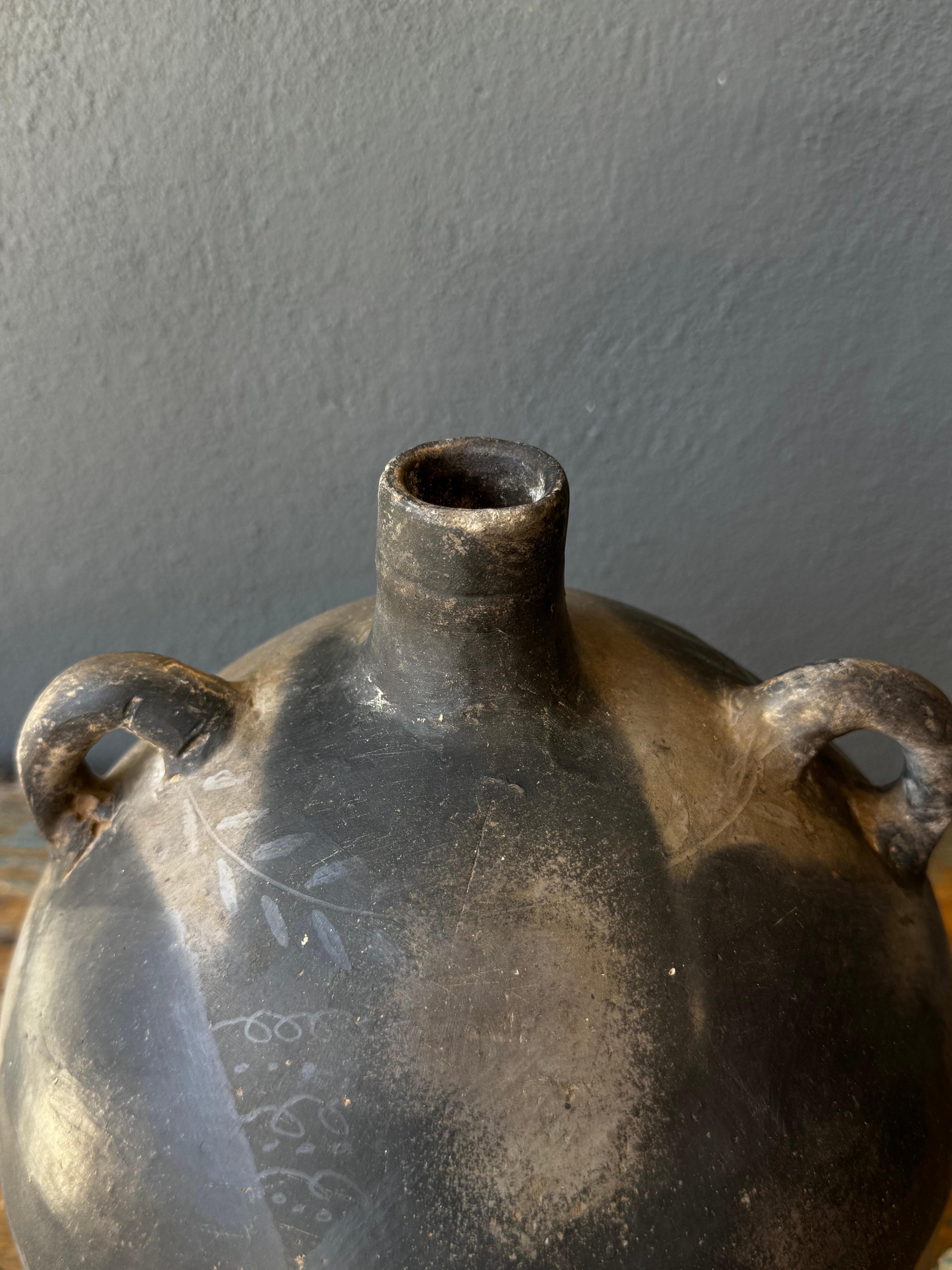 Black clay ceramic mezcal jug from Coyotepec, Oaxaca, circa 1950´s. Rare mezcal jug used for ceremonial or festive reunions. Decorative, leaf markings can be seen around the neck area. Rope would be laced around the handles for portability.
