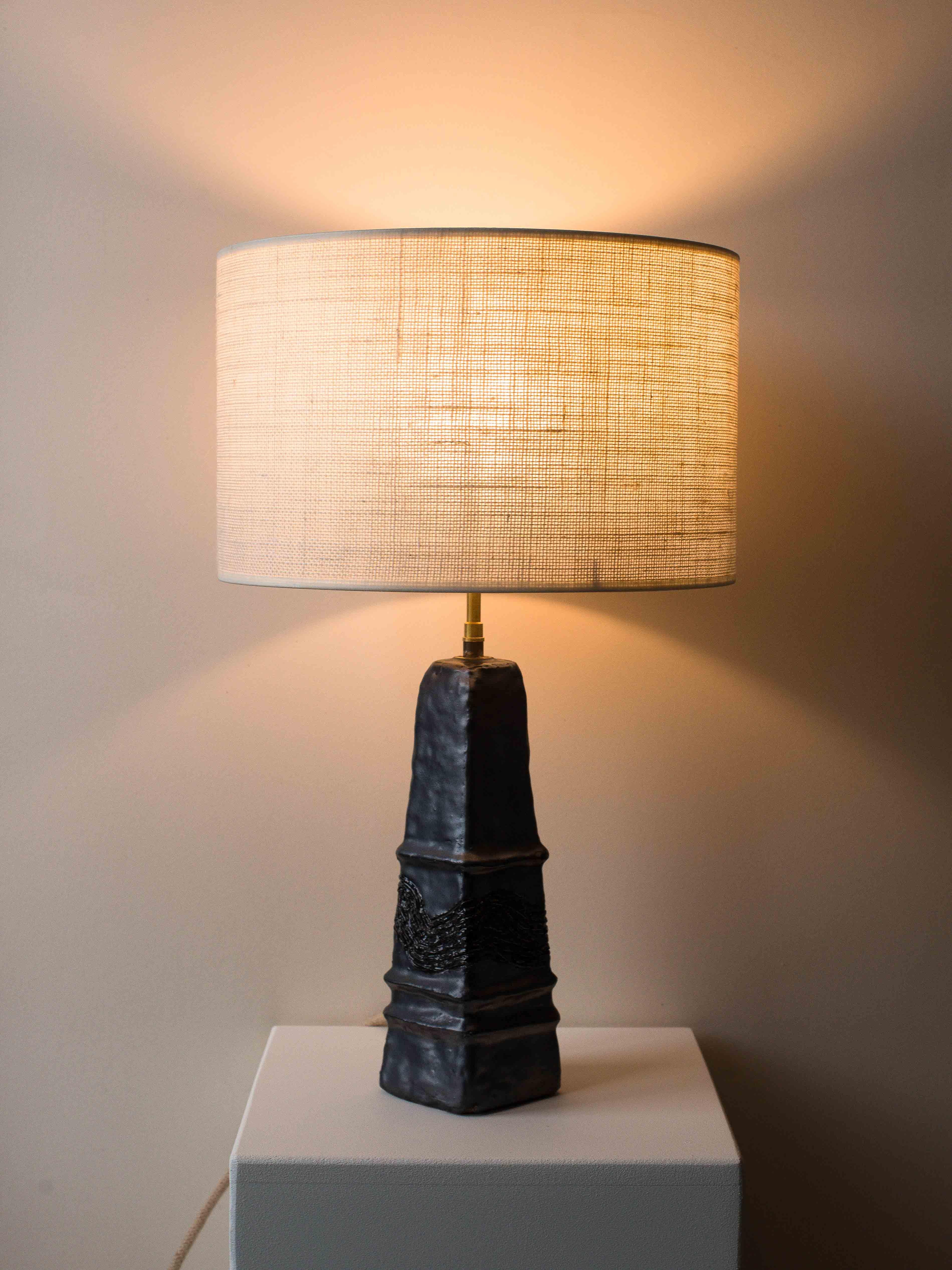 Tischlampe aus schwarzem Ton aus der Mitte des Jahrhunderts, um 1970.

Diese Tonlampe ist ein Einzelstück aus den 1970er Jahren, das von einem französischen Kunsthandwerker handgefertigt wurde. Sein pyramidenförmiges Design und die grafischen Muster