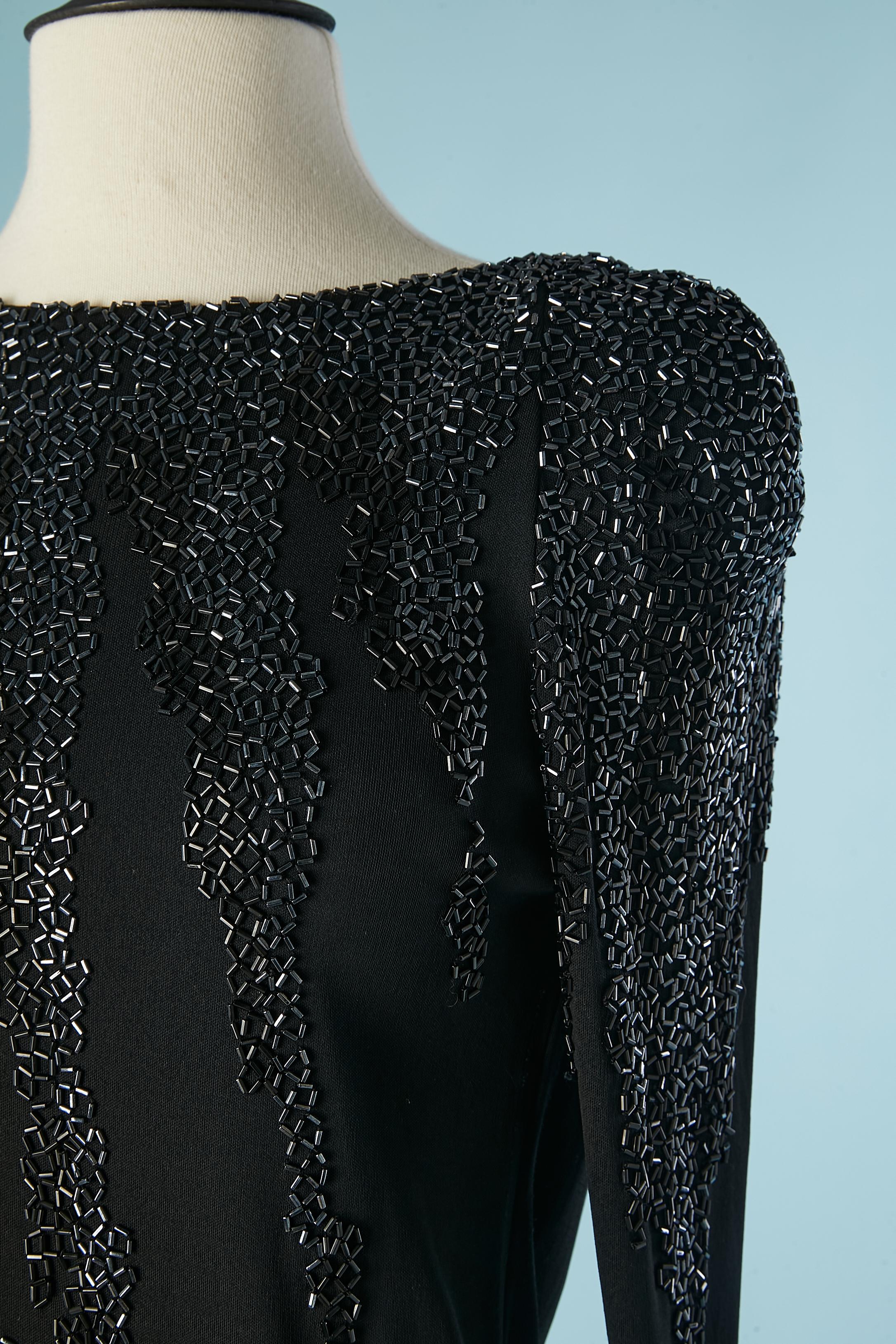 Robe de cocktail en jersey noir avec perles. Même jersey que la doublure. Epaulettes, fermeture à glissière et crochet au milieu du dos. 
Fente au milieu du dos en bas = 8 cm
TAILLE M 