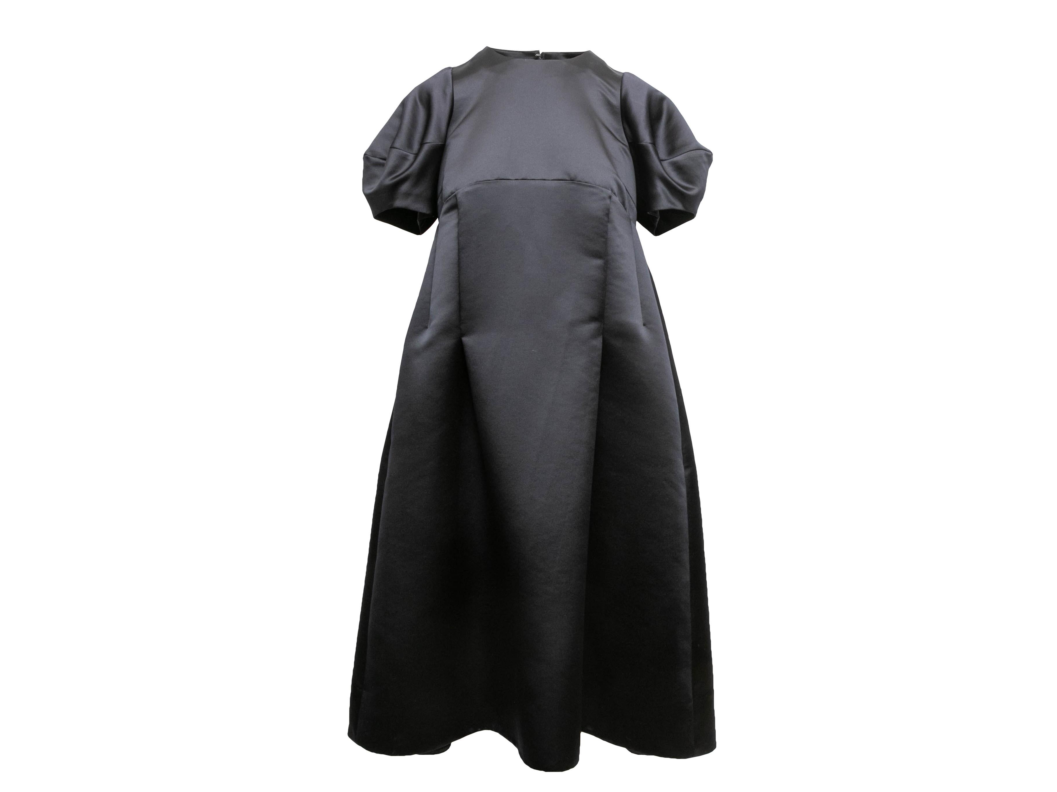 Black satin short puff sleeve dress by Comme Des Garcons. Crew neck. Zip closure at back. 34