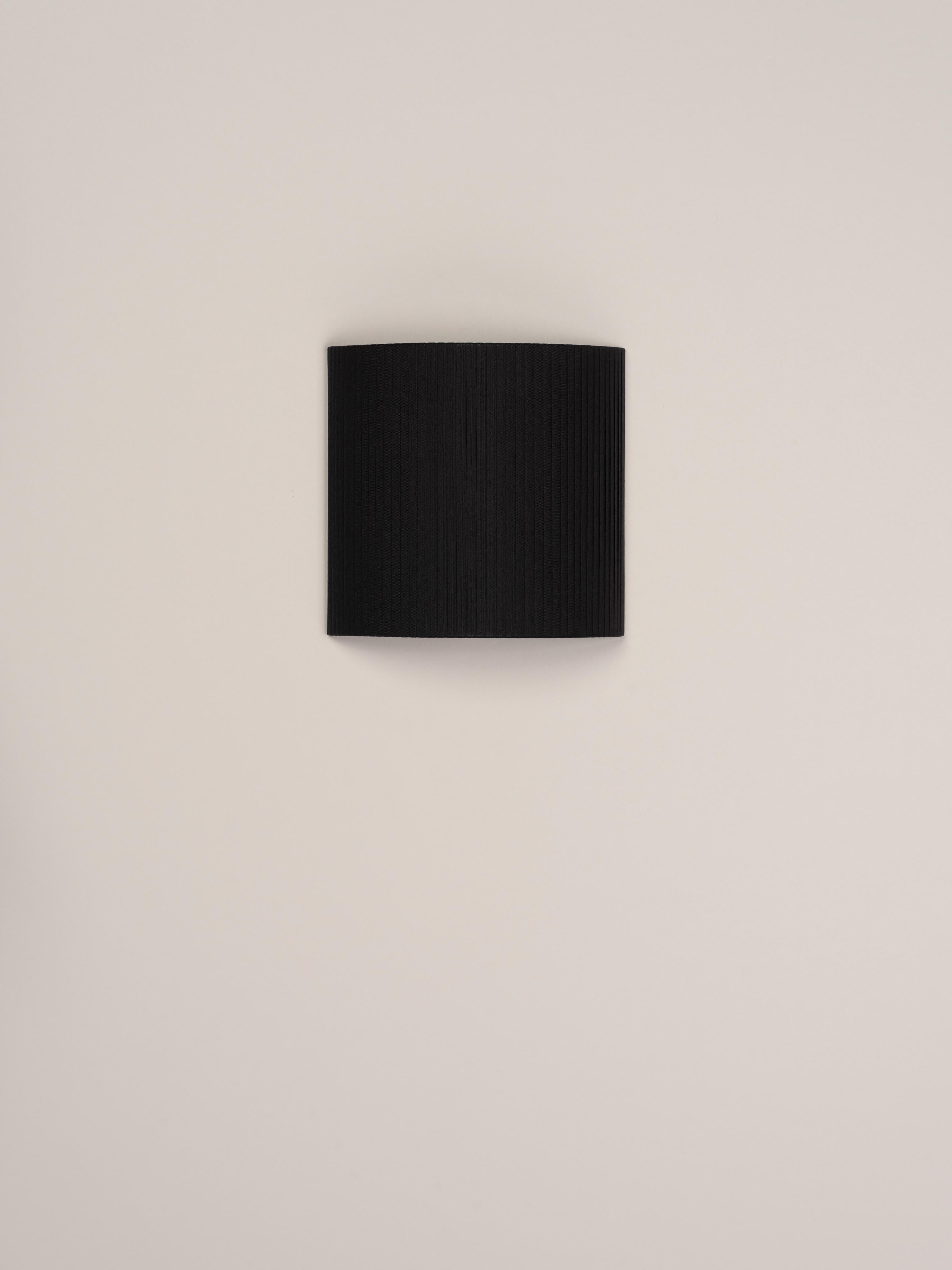 Black comodín cuadrado wall lamp by Santa & Cole
Dimensions: D 31 x W 13 x H 30 cm
Materials: Metal, ribbon.

This minimalist wall lamp humanises neutral spaces with its colourful and functional sobriety. The shade is fondly hand-ribboned, piece