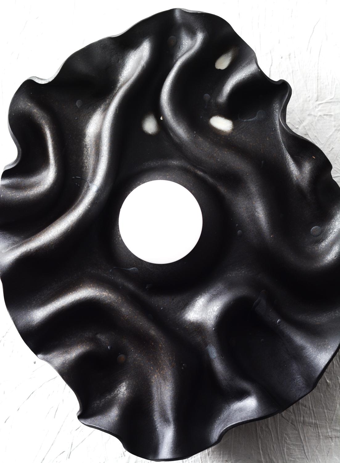 Handgefertigter Wandleuchter aus Keramik mit drapiertem/gefaltetem schwarzem Steinzeugton, der an die natürliche Welt und das Universum erinnert.
Die Natur der Technik, mit der der Ton geformt wird, verleiht jedem Stück einen Hauch von
