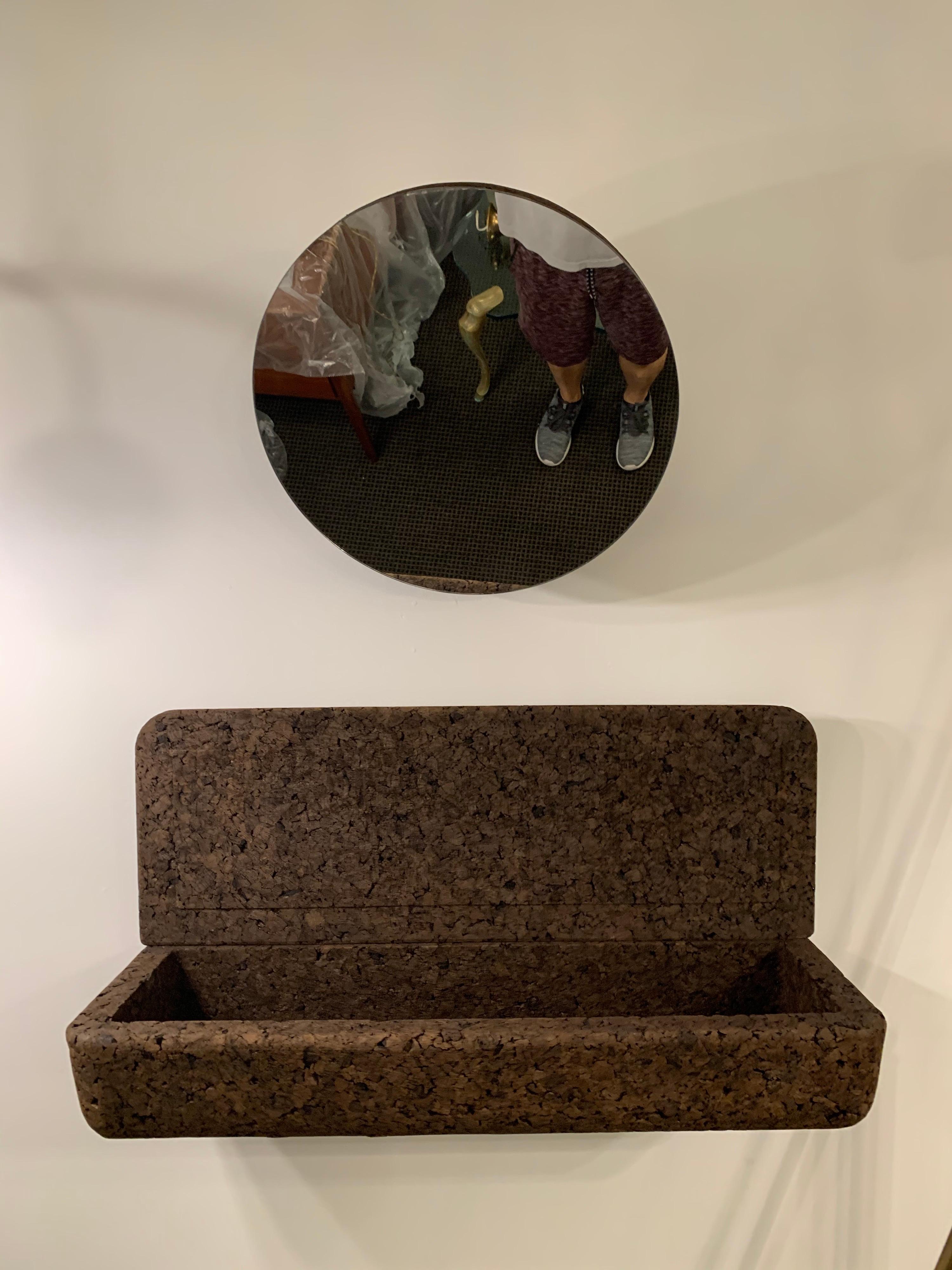 Designed and made in Portugal by Black Cork, this decorative mirror and wall-mounted and lidded shelf are made entirely of locally sourced black cork. The lidded shelf can be covered or left open as a catchall. As pictured in the detail images,