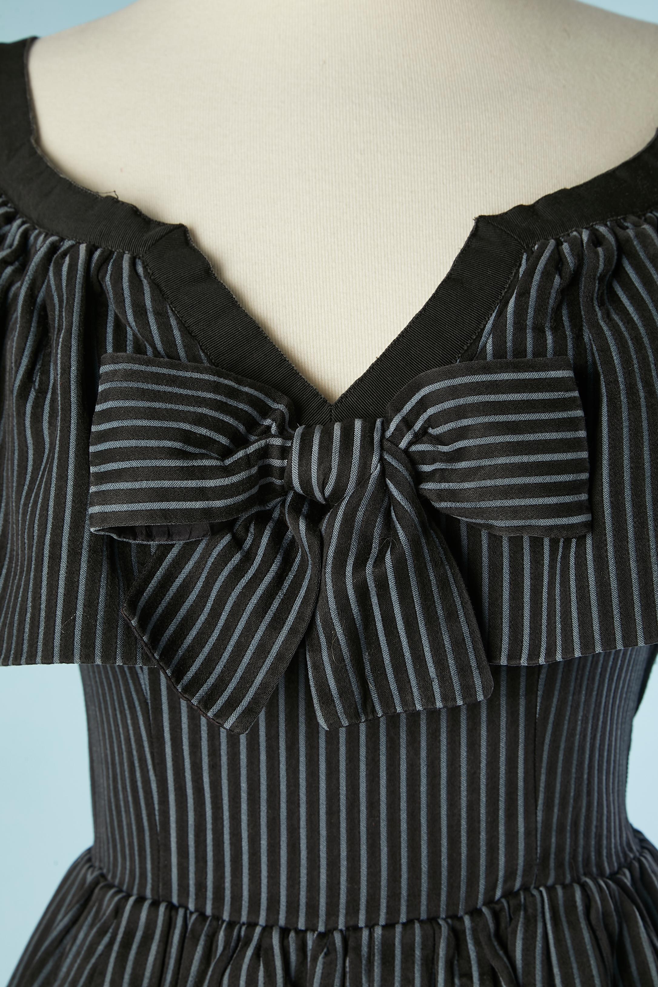 Black cotton dress with blue stripes, ruffles and bow in the middle front.  Boned. Upper cloth: 100% cotton, lining: 100% silk. Zip on the left side. Gros-grain on the edge of neckline and on both side. Ruffles on shoulders. SS 1993
SIZE 36 (6 Us)