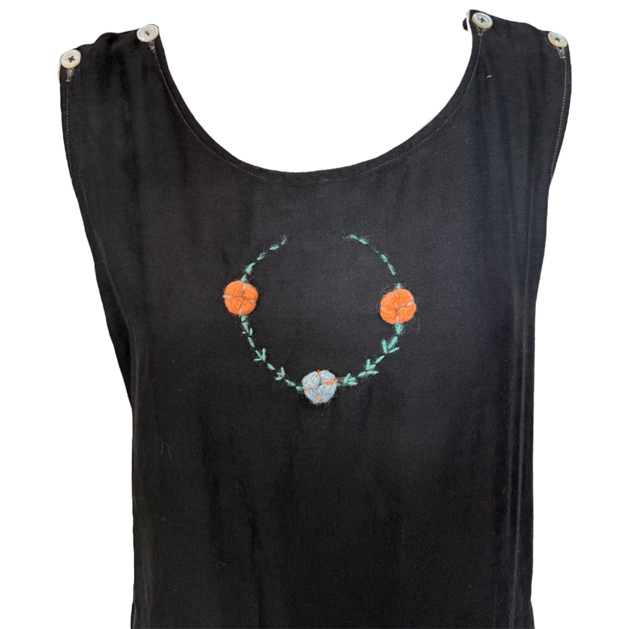 Una rara pieza de la historia de la moda para llevar puesta o guardar en tus archivos. Traje de baño de algodón negro de los años 20 con bordado floral cosido a mano. Cuello redondo con silueta recta y pantalón corto incorporado. Flores naranjas y