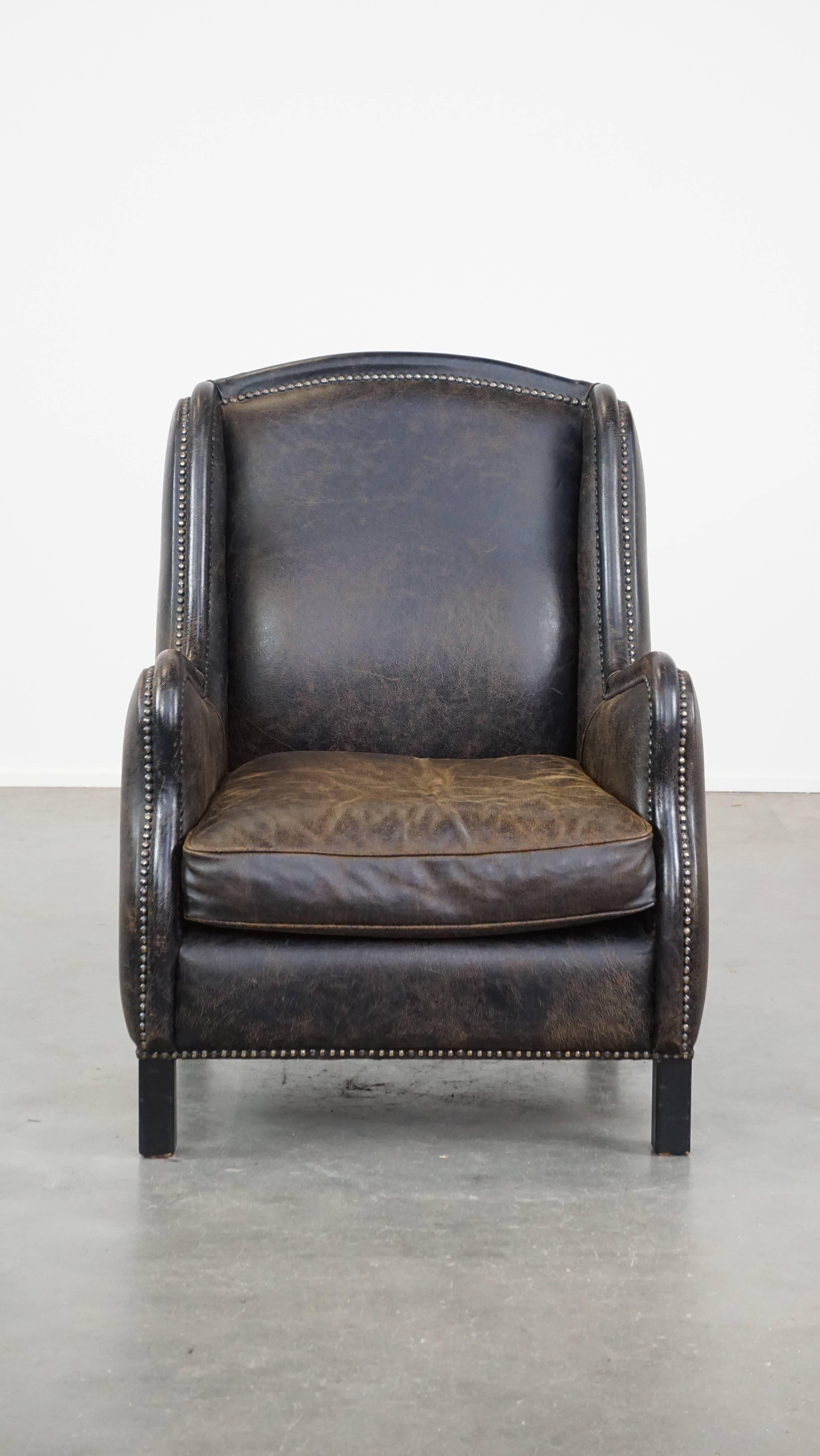 This fantastic black leather armchair can easily fit into nearly any interior. It features a high back and is finished with decorative studs. The armchair is equipped with a loose seat cushion and offers excellent seating comfort. Due to years of