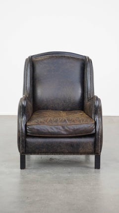 Sillón de cuero vacuno negro acabado con clavos decorativos, estilo industrial