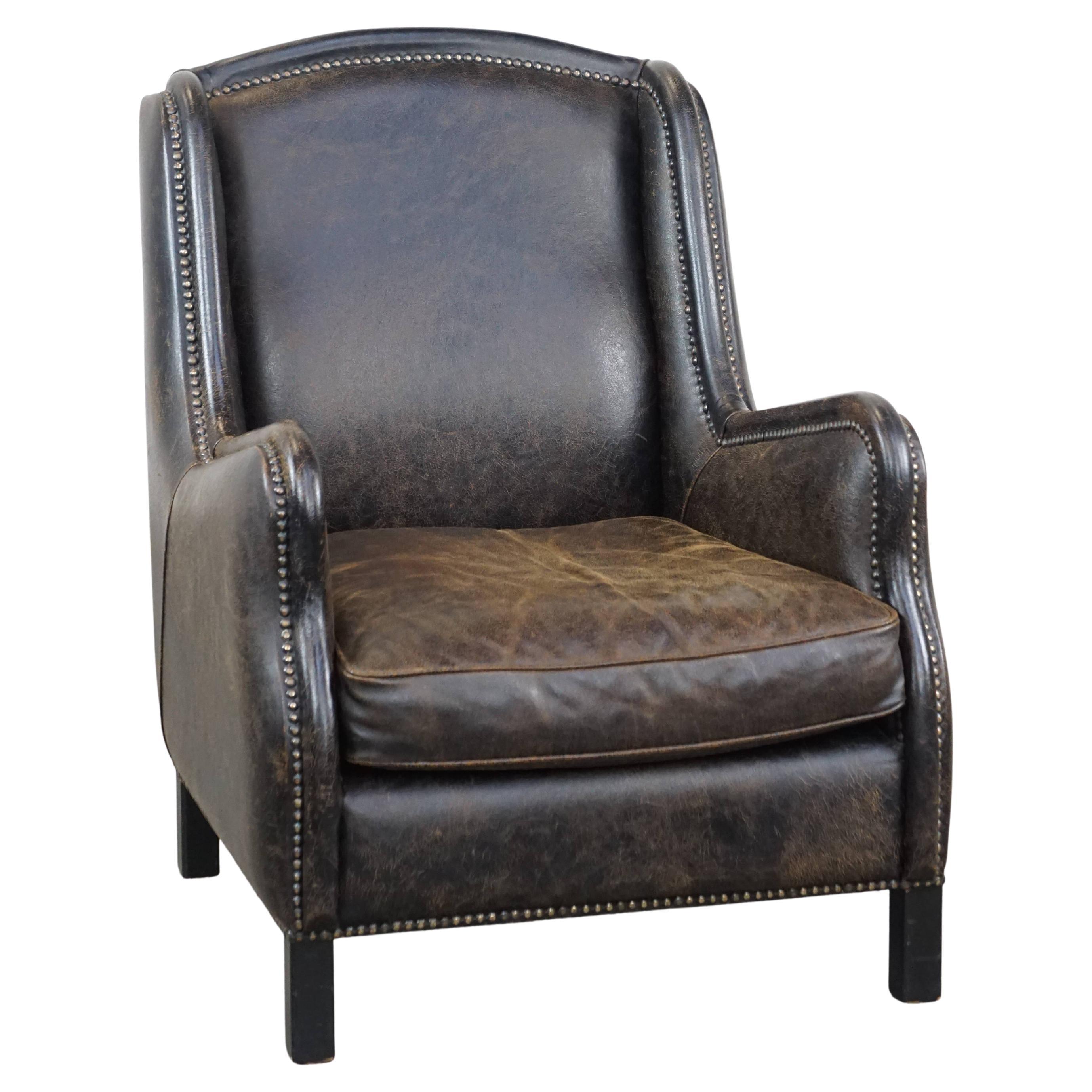 Black cow leather armchair finished with decorative nails, industrial style