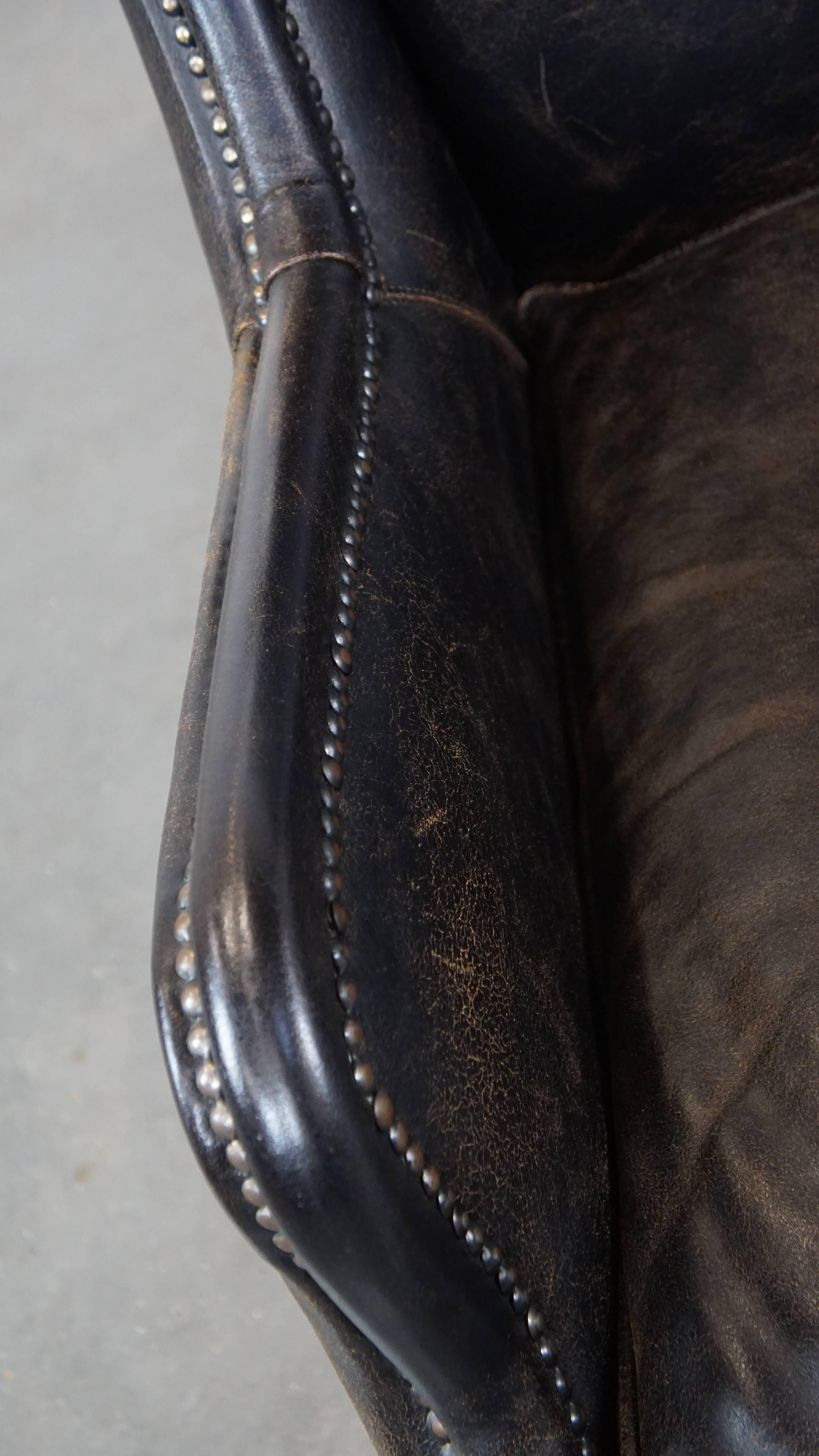 Cowhide Black cow leather armchair in industrial style finished with decorative nails For Sale