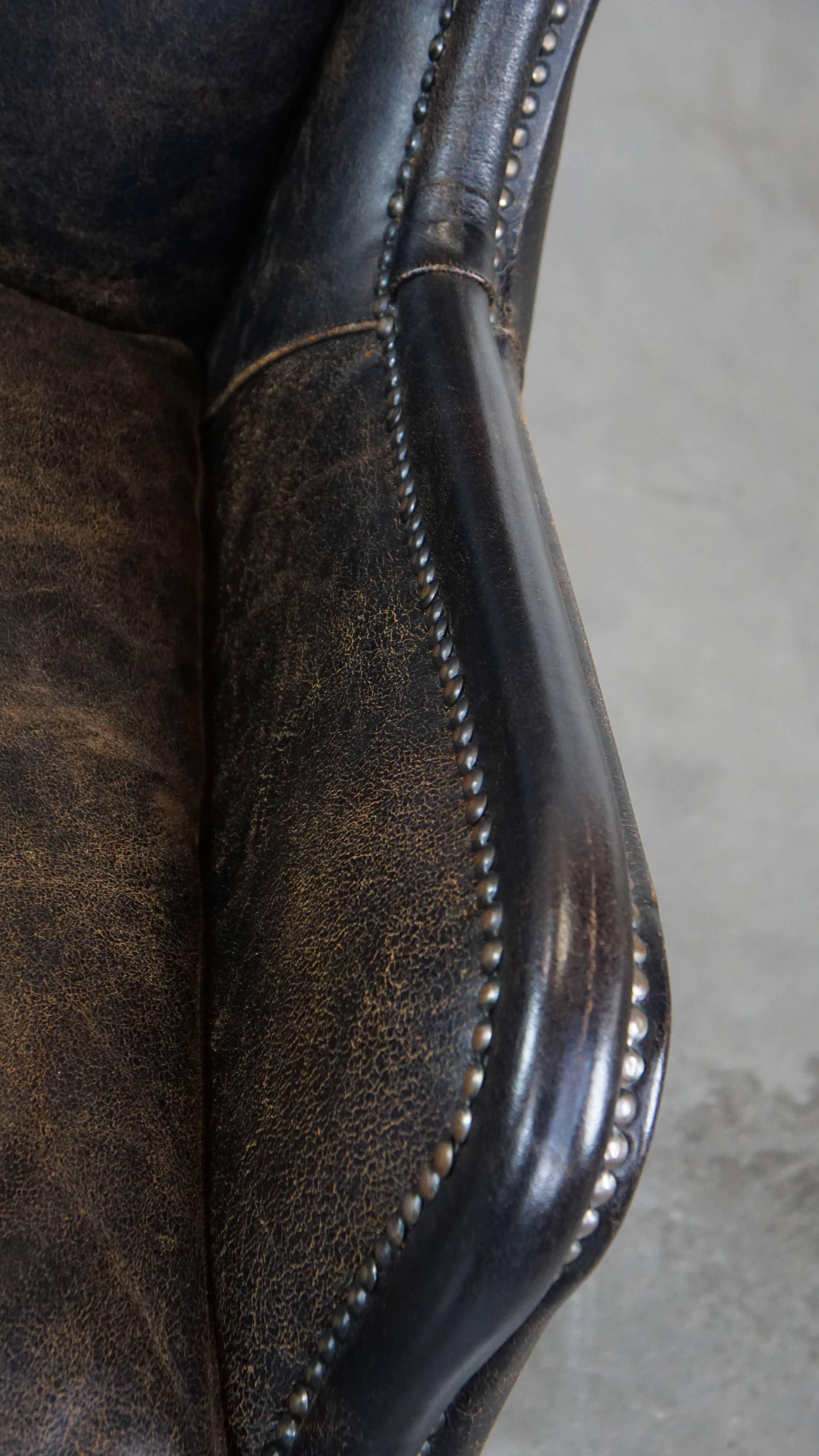 Black cow leather armchair in industrial style finished with decorative nails For Sale 1