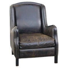 Black cow leather armchair in industrial style finished with decorative nails