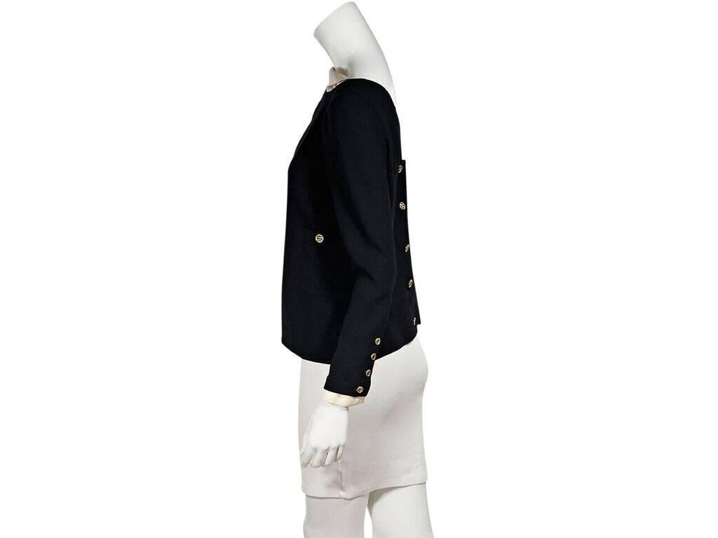 Product details:  Black blouse with cream trim by Chanel.  Boatneck.  Long sleeves.  Four-button detail at cuffs.  V-back.  Button back closure.  38