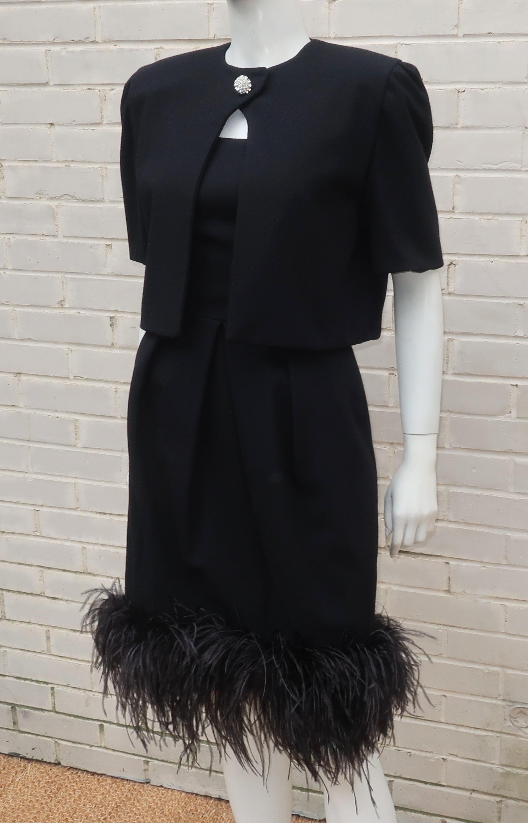 C.1980 black wool crepe cocktail dress with a marabou feather trimmed hem and a coordinating cropped jacket with a rhinestone button.  The dress zips and hooks at the back with inverted pleating which provides the hint of a bubble skirt.  The short