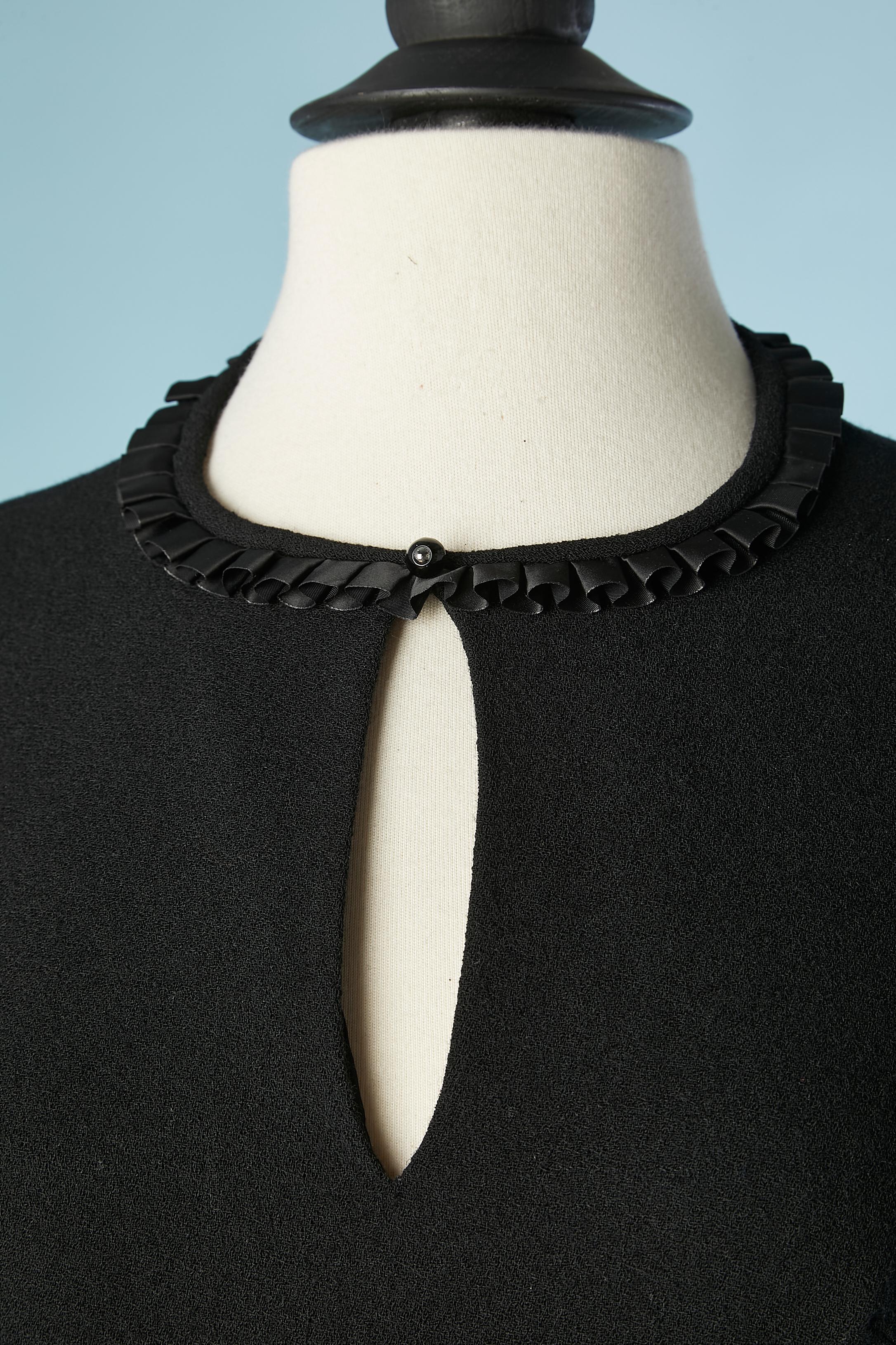 Robe de cocktail en crêpe noir avec des volants de rubans noirs sur les manches, l'encolure et les poches. Fermeture éclair au milieu du dos et crochet et œillet. Doublure en acétate.
TAILLE S