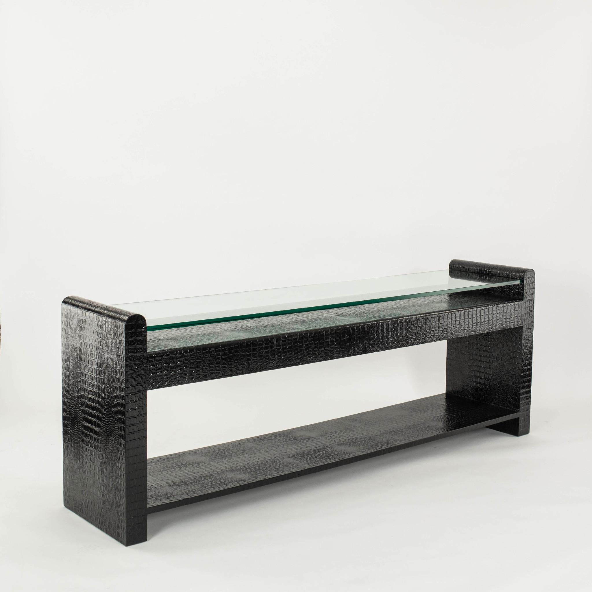 A handsome and stately black crocodile embossed leather console with 3/4