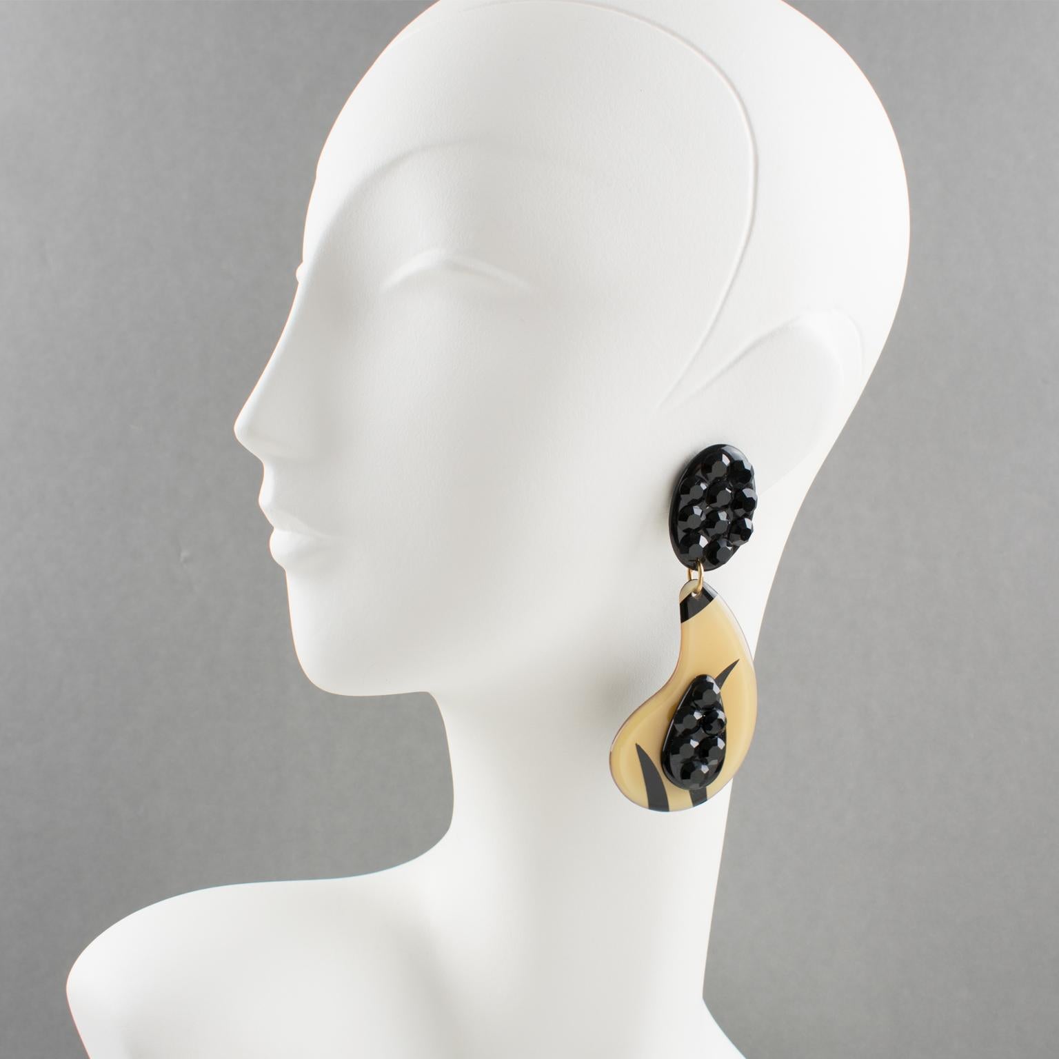 These charming Italian designer studio Lucite dangling clip-on earrings feature an oversized teardrop shape in custard beige color with black stripes design. The earrings are also ornate with licorice black crystal rhinestones. Those are total