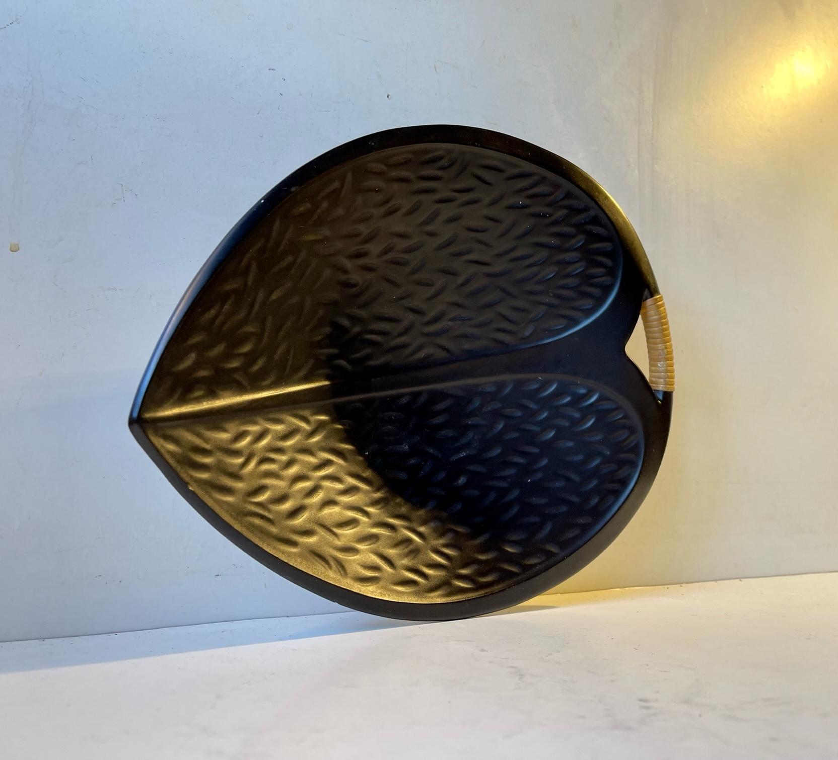 Stylized satin black glazed asymmetrical leaf bowl set with contrasting rattan to its small handle. Designed by Ivar Jensen for his Studio Hedehus Keramik in Denmark circa 1960. Measurements: W/D: 23/27 cm, Height: 8 cm.