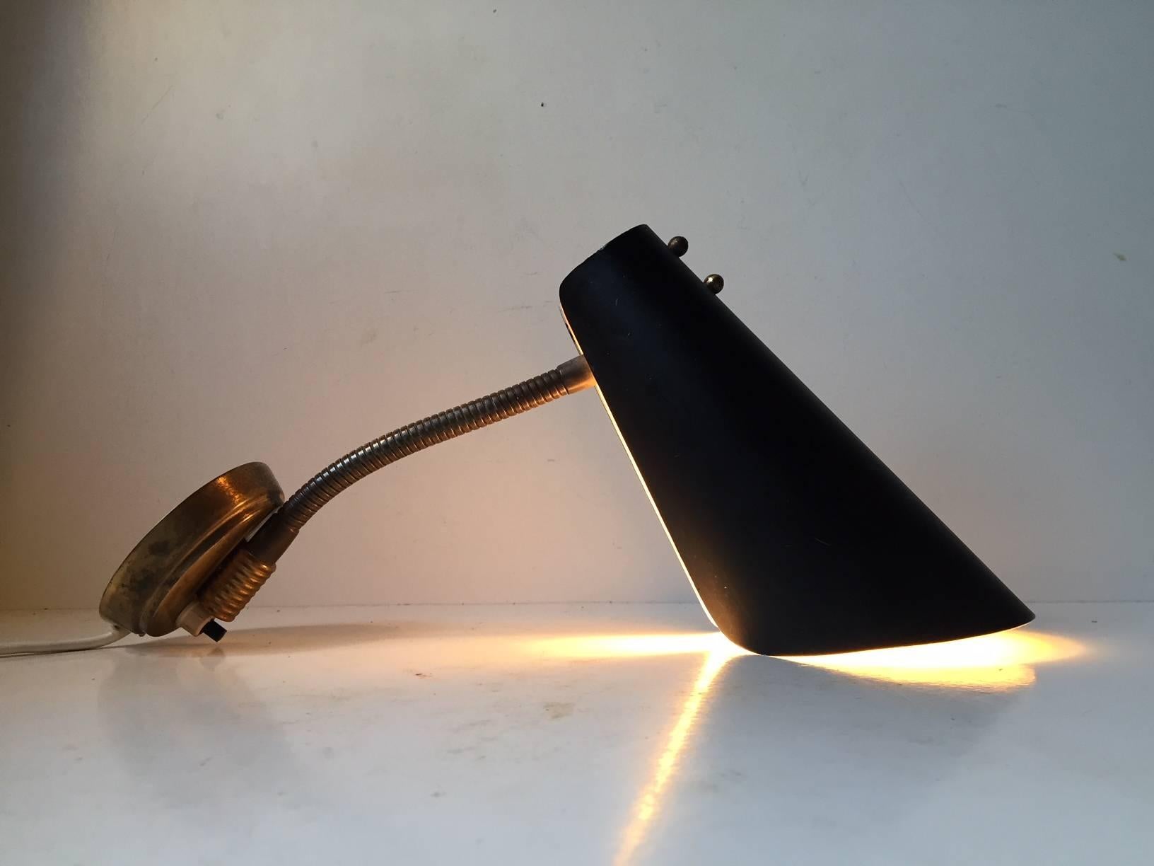 Cette applique réglable a été conçue et fabriquée par Fog & Mørup au Danemark dans les années 1950. La lampe est dotée d'un abat-jour noir mat plié et d'un col de cygne flexible en laiton. Le design a été inspiré par le fabricant italien Stilnovo,
