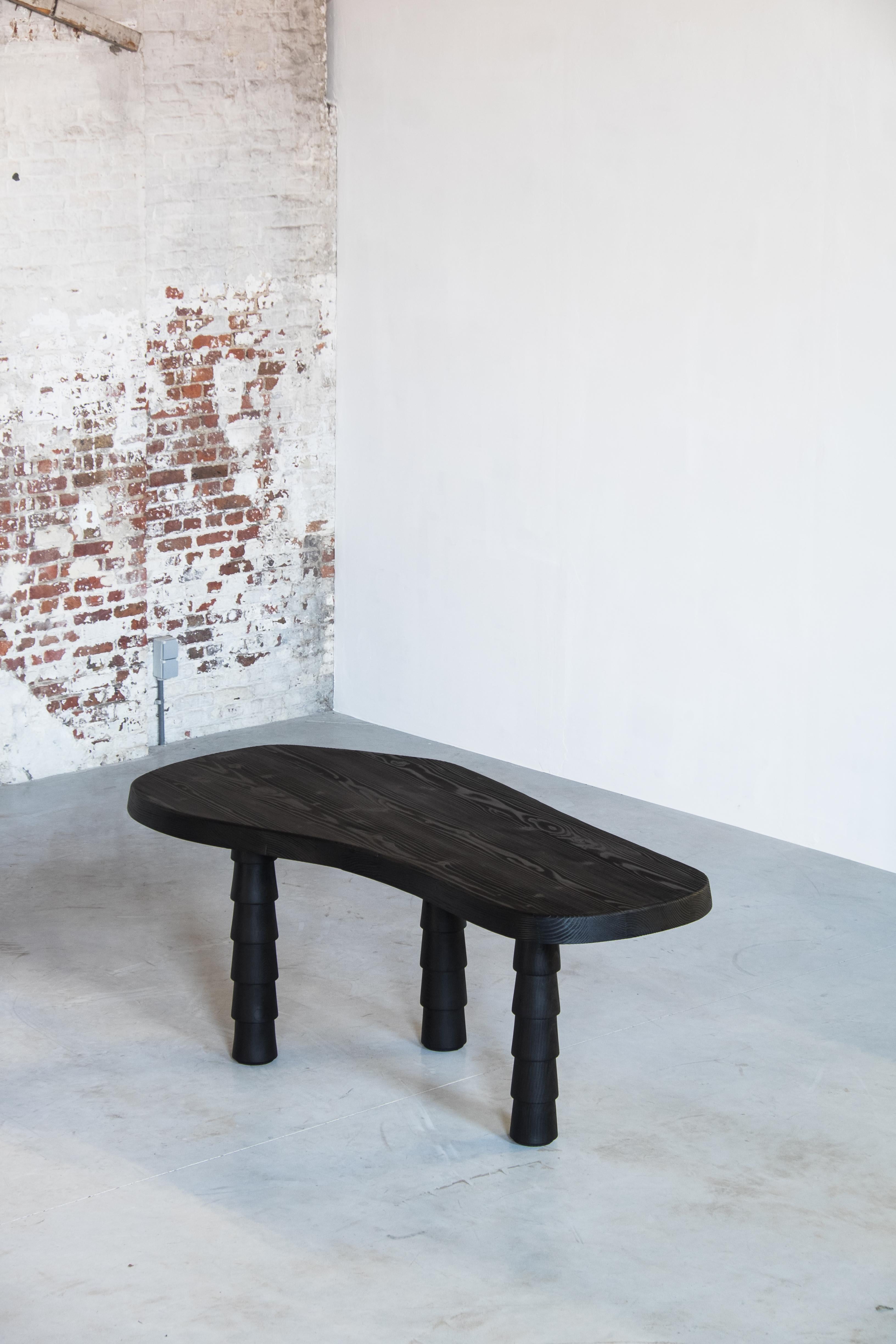 Black data table three legged in Oregon by Atelier Thomas Serruys
Dimensions: L 180 x D 94 / 63 x H 75 cm 3 legs
Materials: Free shaped top in solid Oregon with smooth round edges
Ebonized by burning
4persons
Demountable hand turned trapezoid