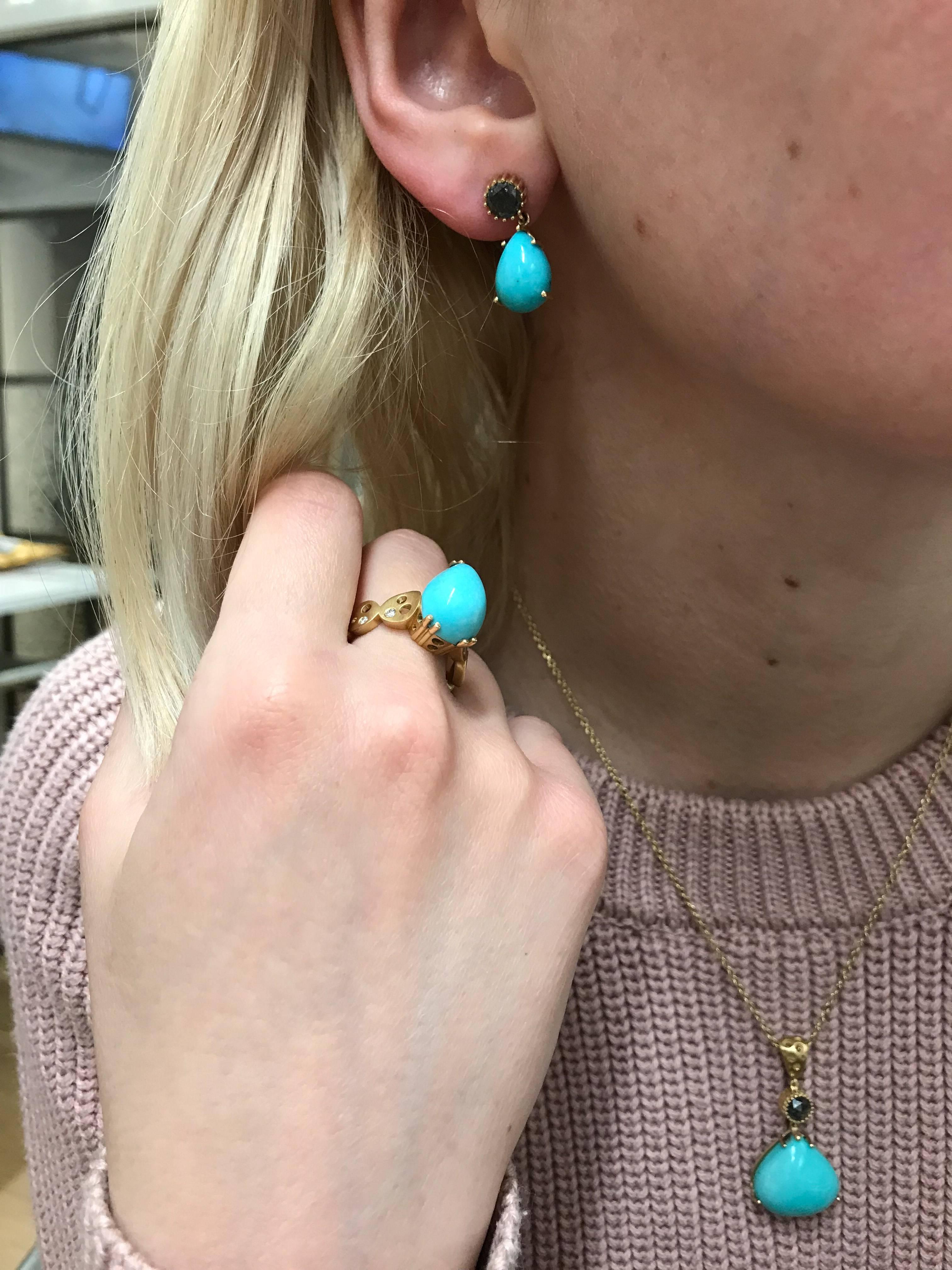 A small pear-shaped sleeping beauty turquoise (4.1 carats each) dangles from a rose cut black diamond (.72 carats each). 18 karat yellow gold prongs hug the stones in these delicate drop earrings. Small and light, they 